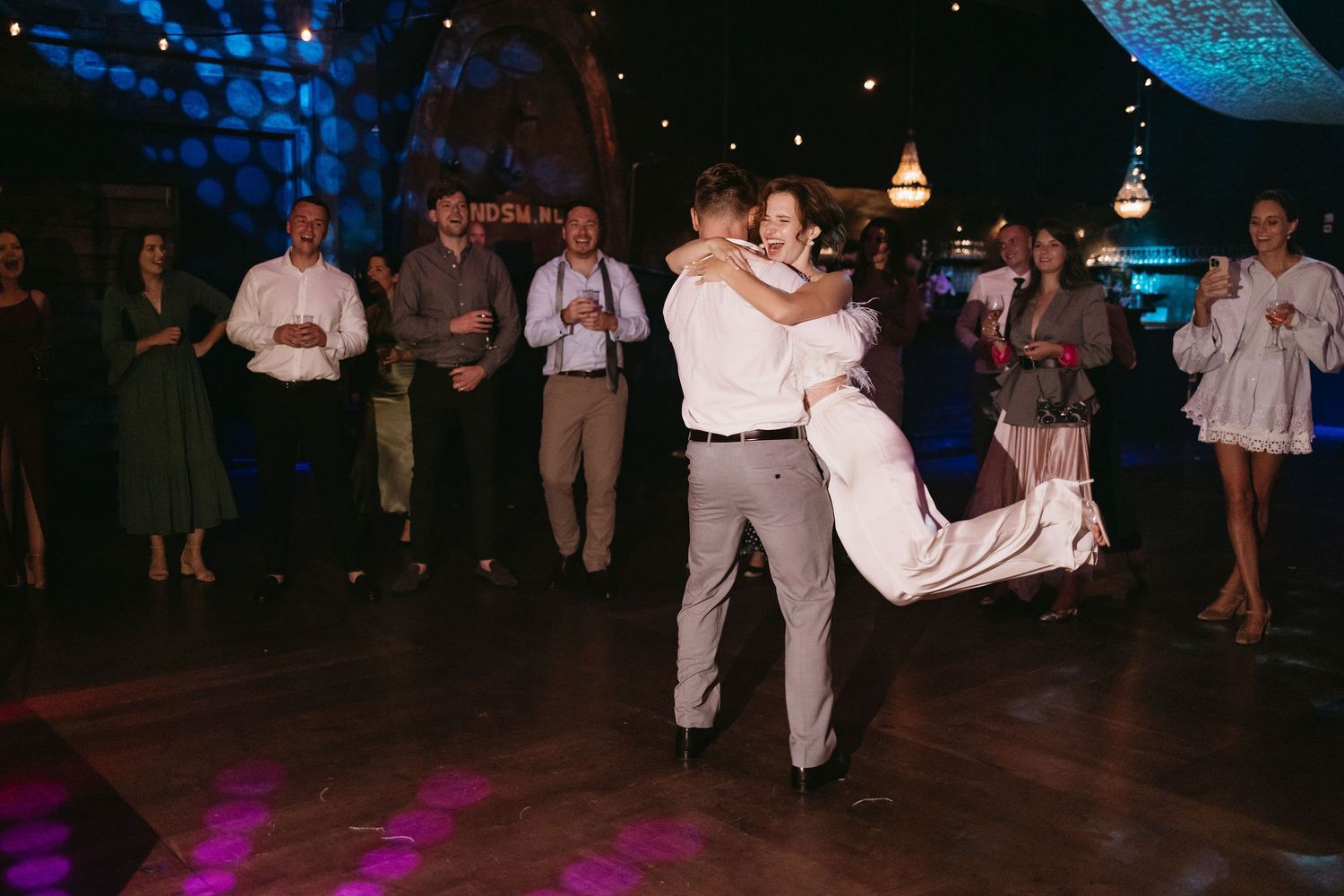 Wedding reception dance floor with blue lighting and guests dancing.