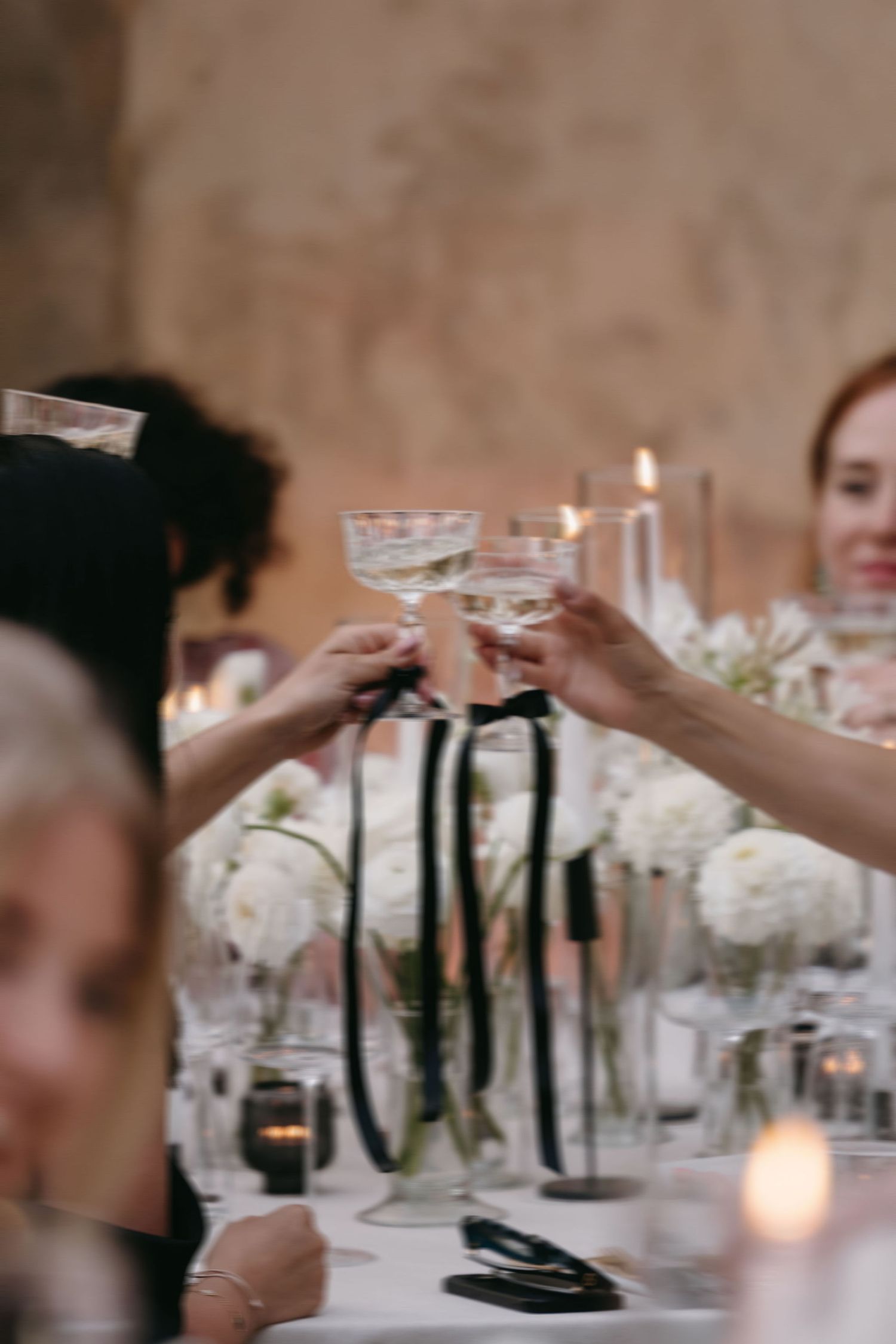 Elegant table settings with white floral centerpieces and glowing candles at dusk.