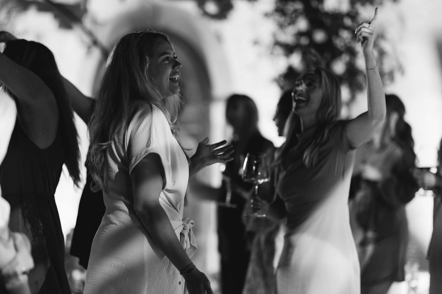 Black and white photo of guests dancing at an evening outdoor celebration.