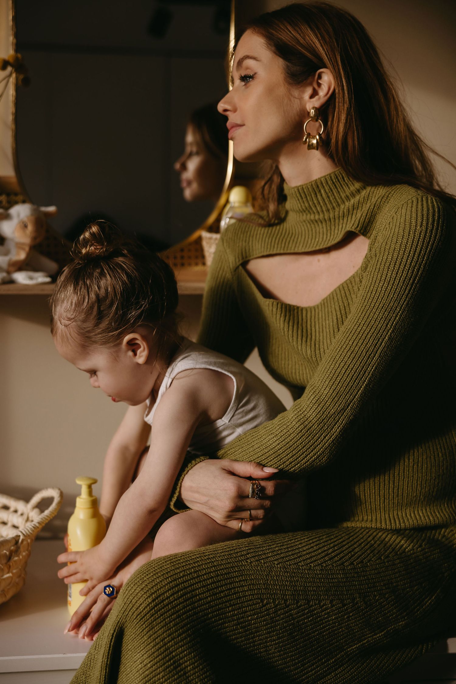 Mother and child sharing tender moment while sitting together in olive green sweater.