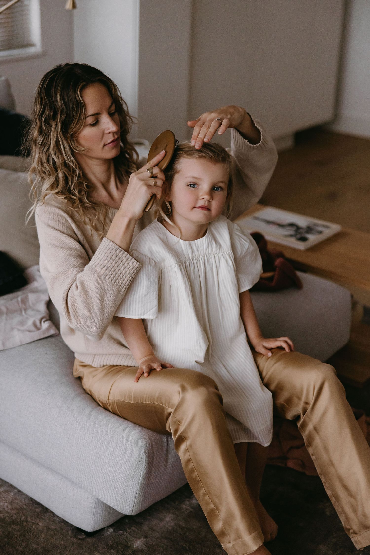 Intimate lifestyle photos show gentle moments between family members on a light colored sofa.