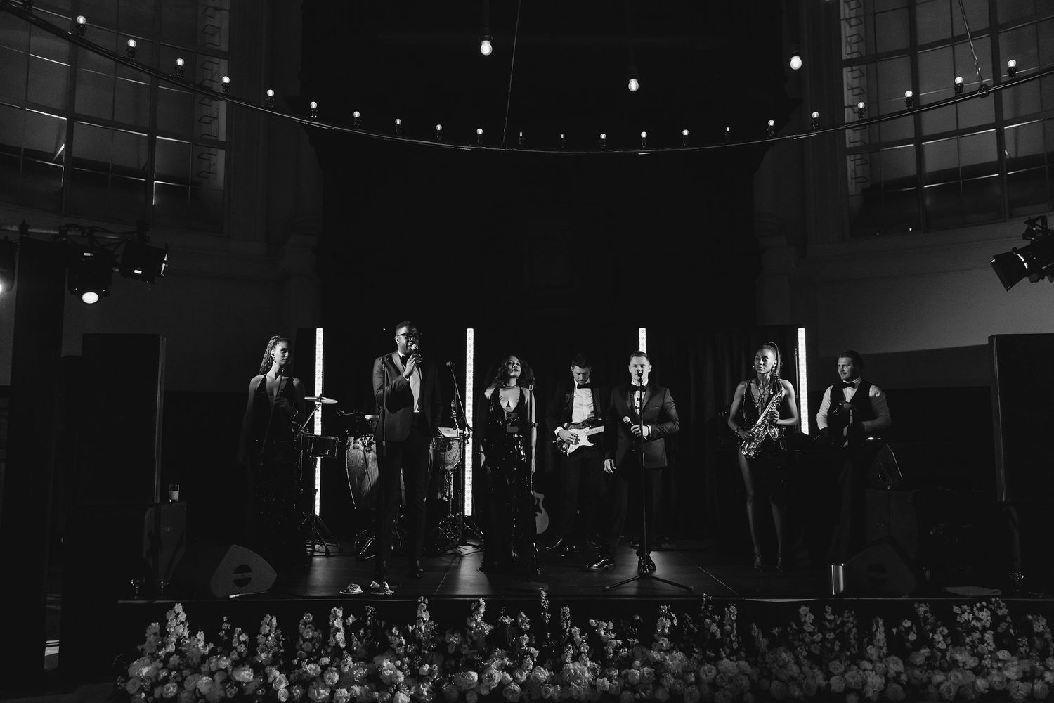 Dark venue with string lights and audience silhouettes during an evening event.