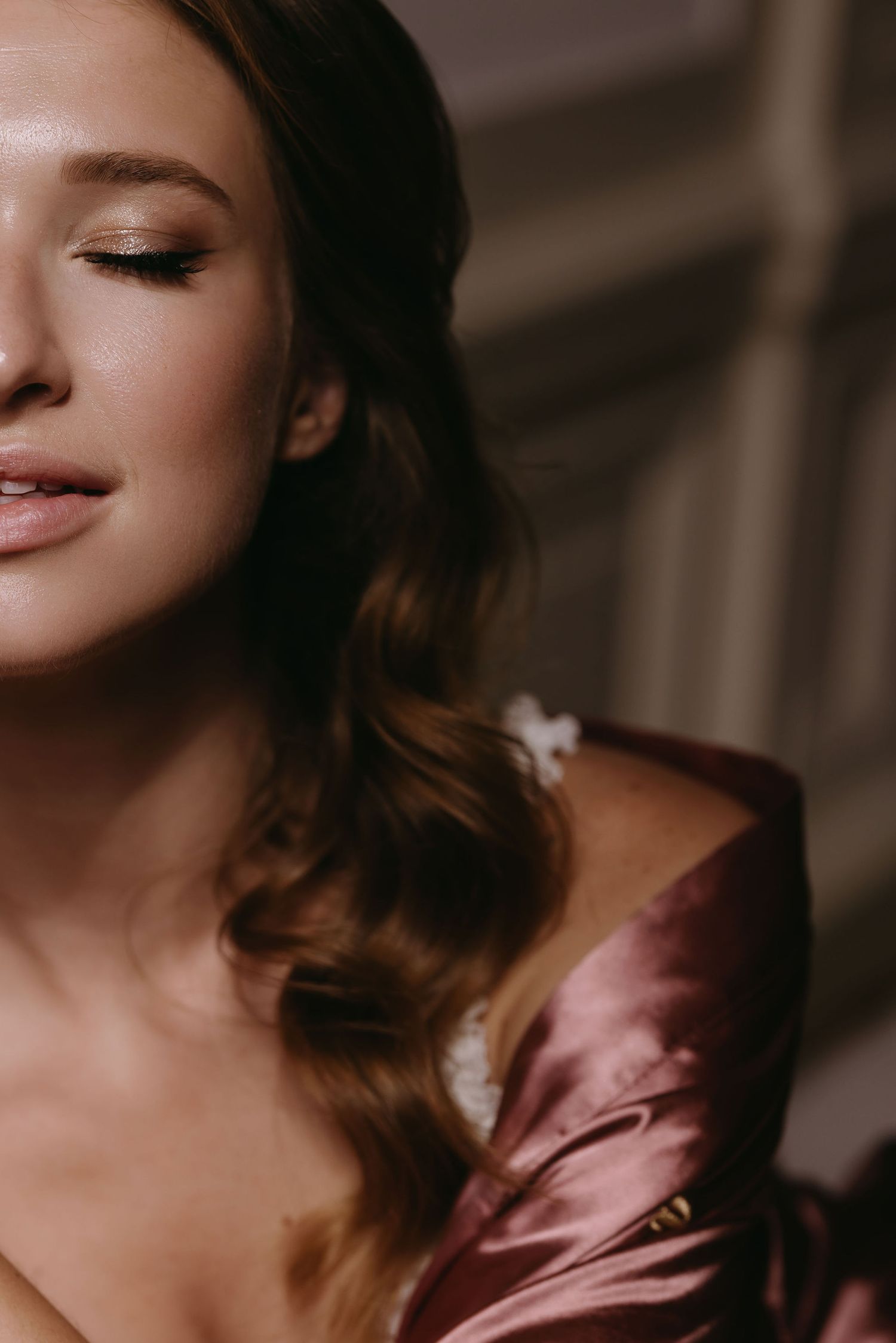 Close-up portrait featuring soft makeup and a silk burgundy dress.