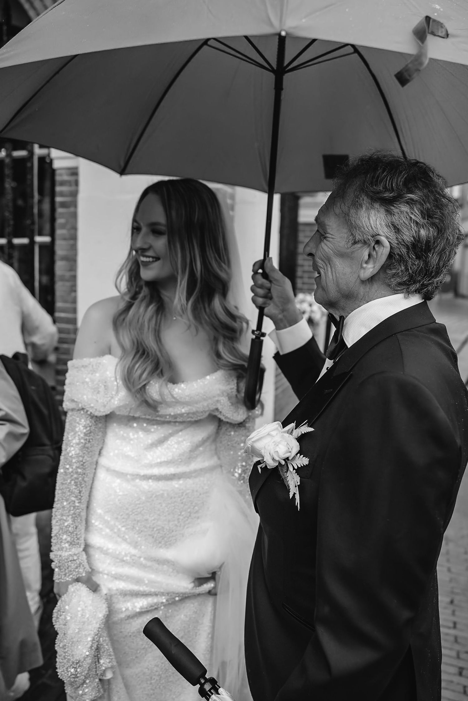 Wedding couple under white umbrella sharing joyful moment during outdoor celebration.