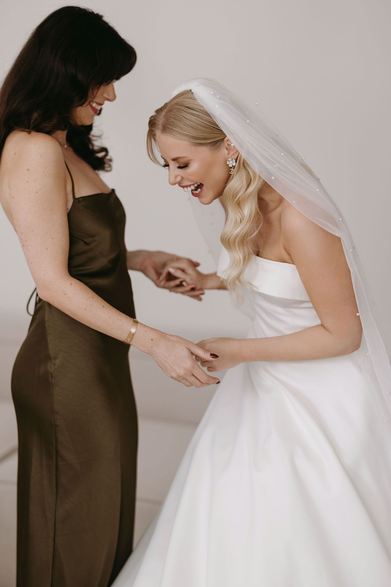Wedding dress preparation moments with attendant helping adjust the gown.
