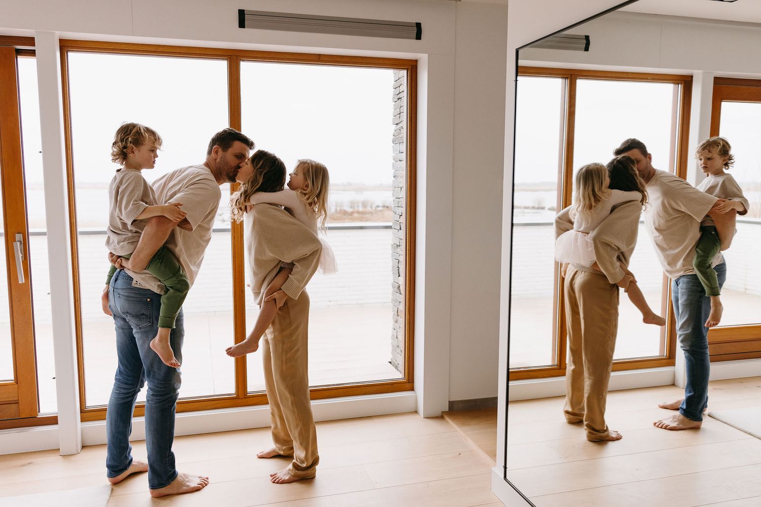 A tender family moment shared while standing by large windows in a bright, minimalist room.