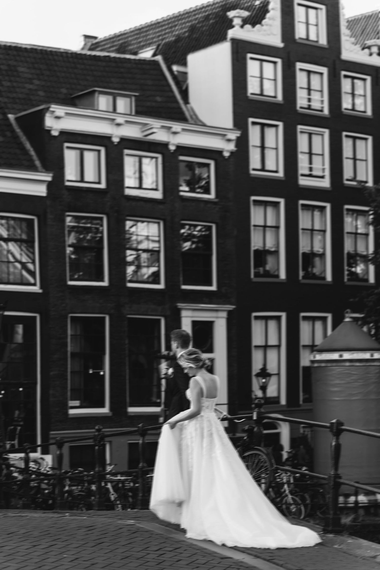 Wedding couple posing in front of traditional Dutch architecture with bicycles and canal houses.