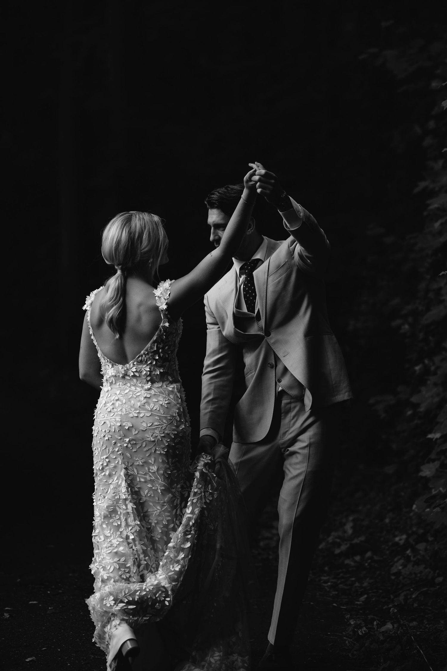 Romantic black and white photo of couple dancing together in formal attire.