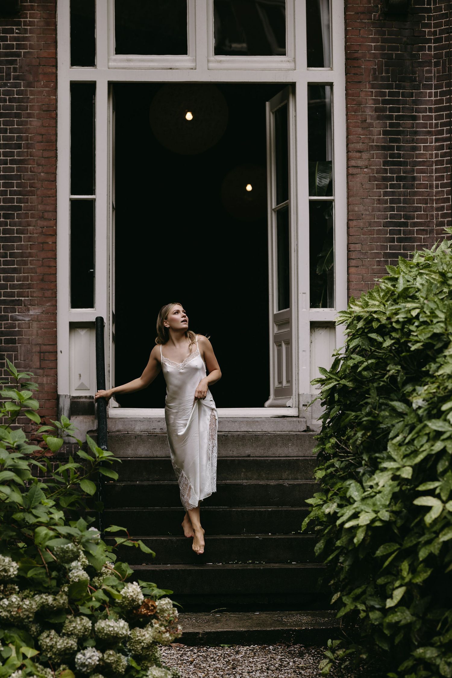 Artistic wedding photos showing bride exploring exterior of historic brick building.