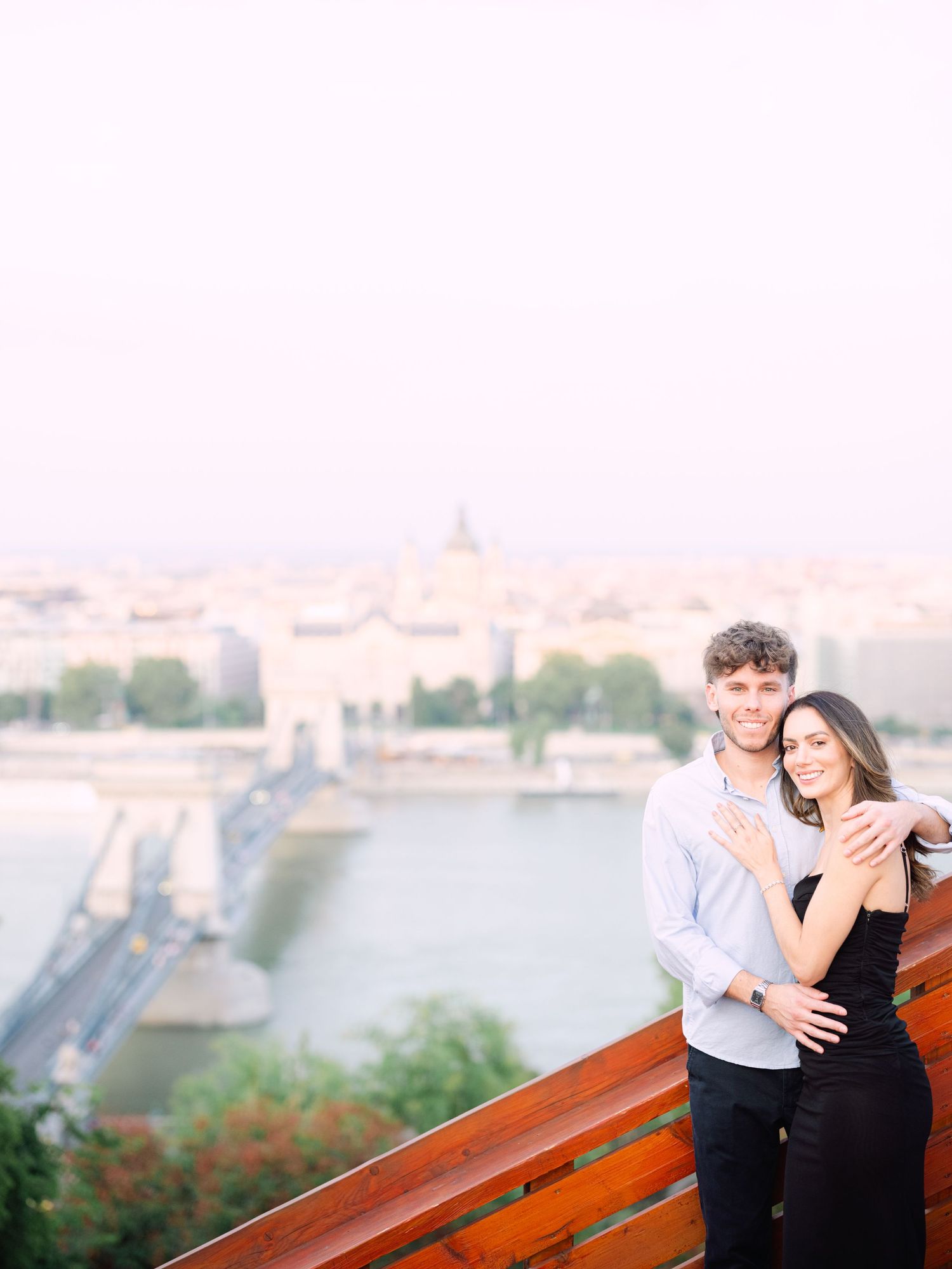Elegant couple laughing and posing around Buda Castle in Budapest with scenic city views in the background during an couple portrait session