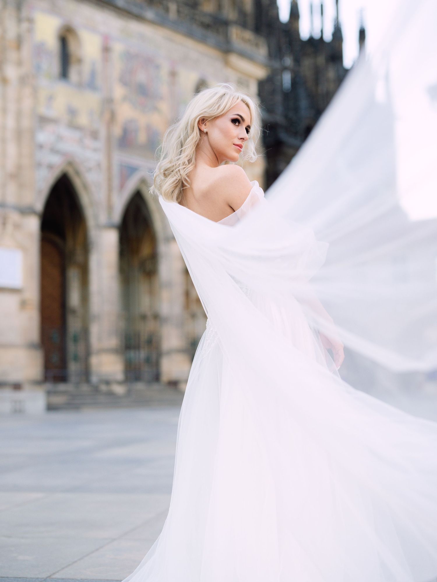 Dynamic bride in a Kozarics Viktor dress posing at Prague Castle for a destination wedding, beautifully captured by Hang Pham Photography