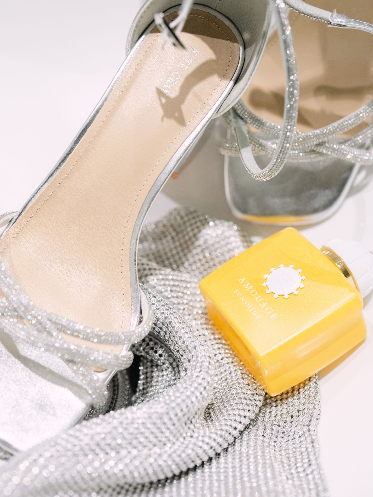 Wedding flatlay featuring elegant bridal shoes and a bottle of Amouage perfume, styled for a luxurious wedding detail shot