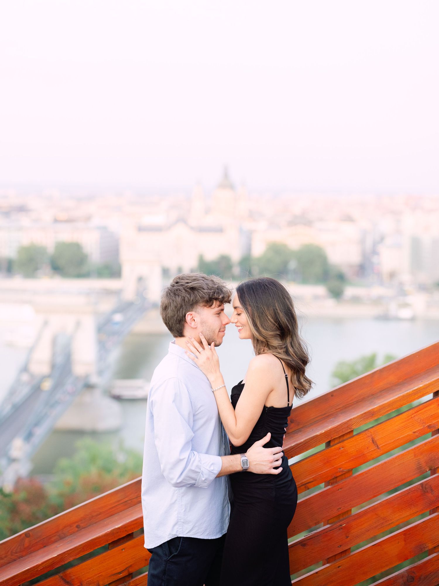 Elegant couple laughing and posing around Buda Castle in Budapest with scenic city views in the background during an couple portrait session