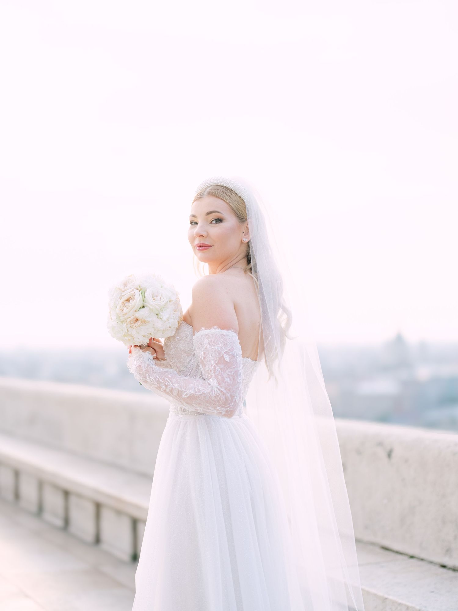 Captivating bride in a La Mariée dress posing at sunrise on Fisherman’s Bastion in Budapest during a pre-wedding session by Hang Pham