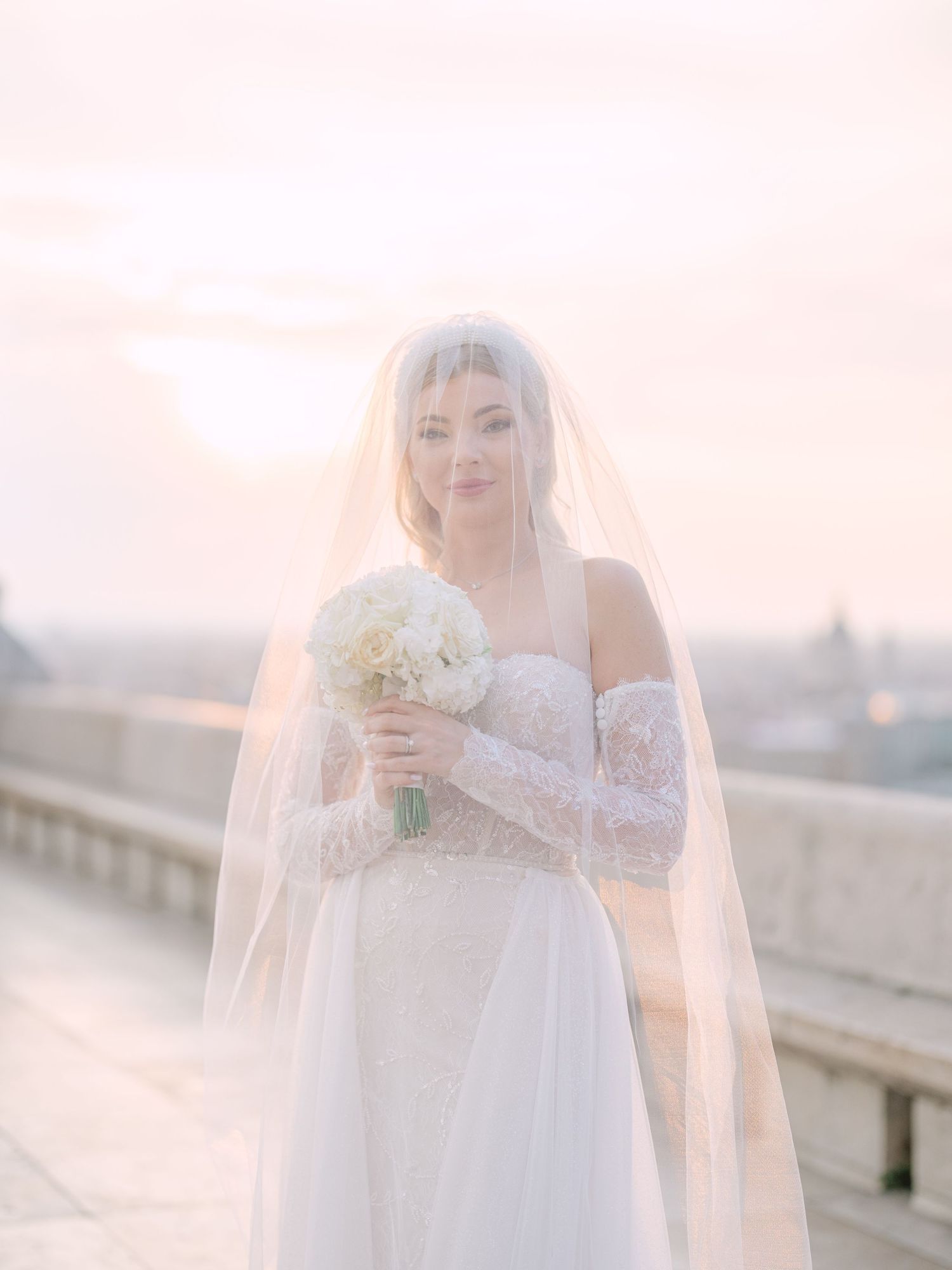 Captivating bride in a La Mariée dress posing at sunrise on Fisherman’s Bastion in Budapest during a pre-wedding session by Hang Pham