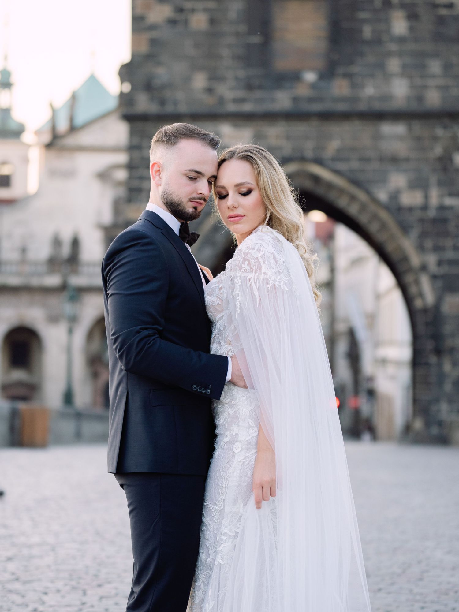 Elegant couple posing on Charles Bridge in Prague during a luxury destination wedding editorial, captured beautifully by Hang Pham