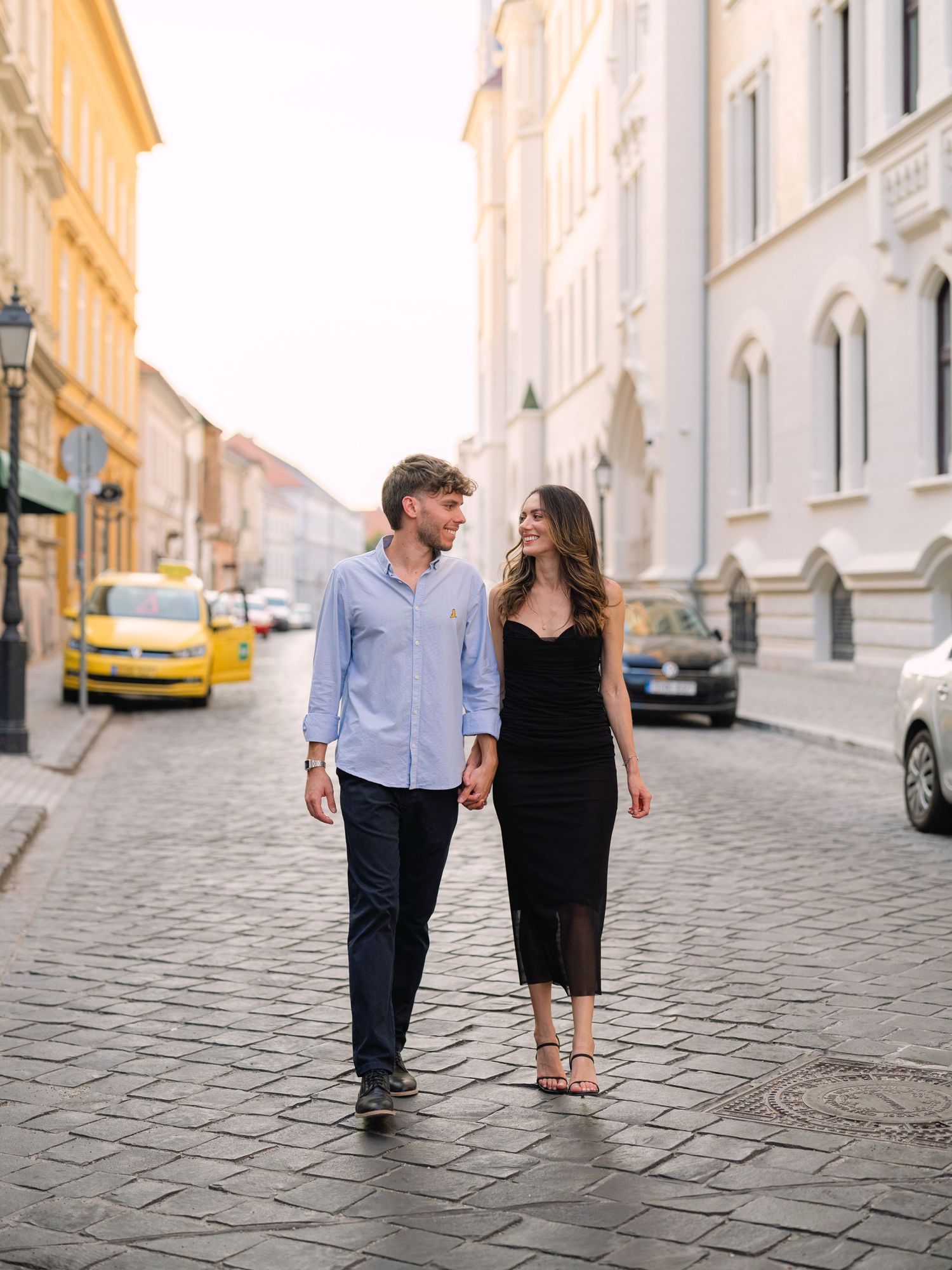 Elegant couple laughing and posing around Buda Castle in Budapest with scenic city views in the background during an couple portrait session