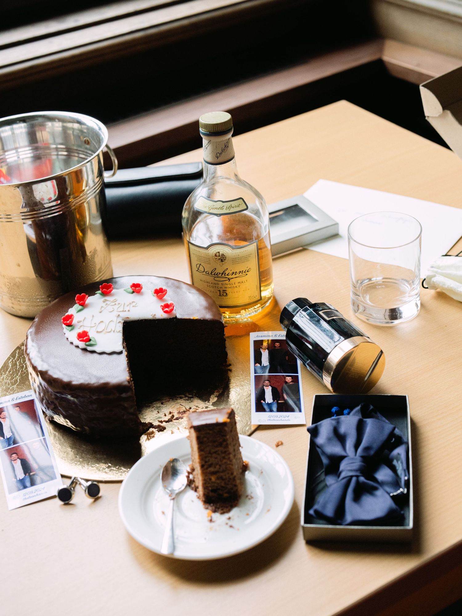 Groom’s wedding flatlay featuring Dalwhinnie whiskey, bowtie, parfum, elegant accessories, and a cake styled for luxury detail photography