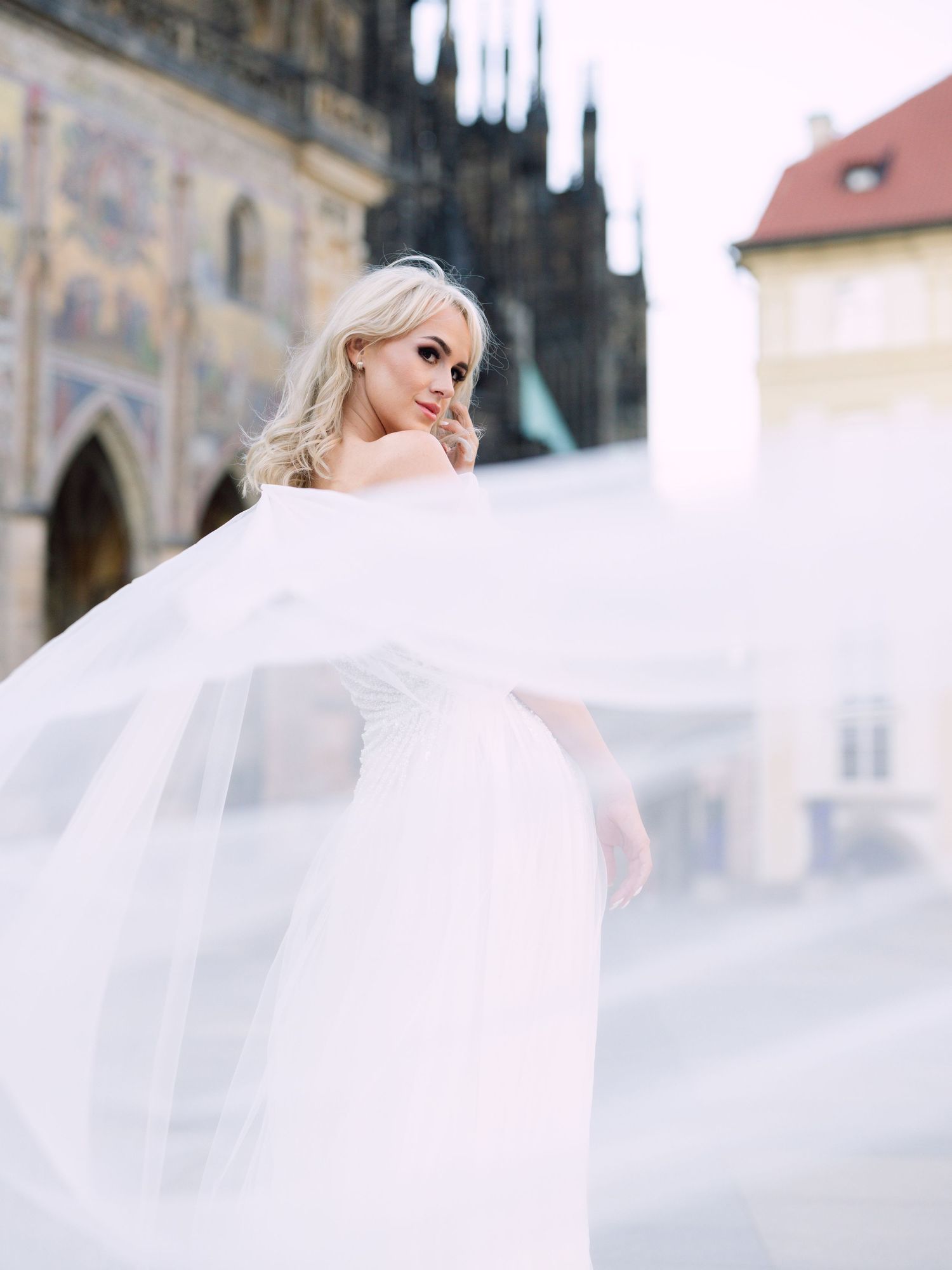 Dynamic bride in a Kozarics Viktor dress posing at Prague Castle for a destination wedding, beautifully captured by Hang Pham Photography