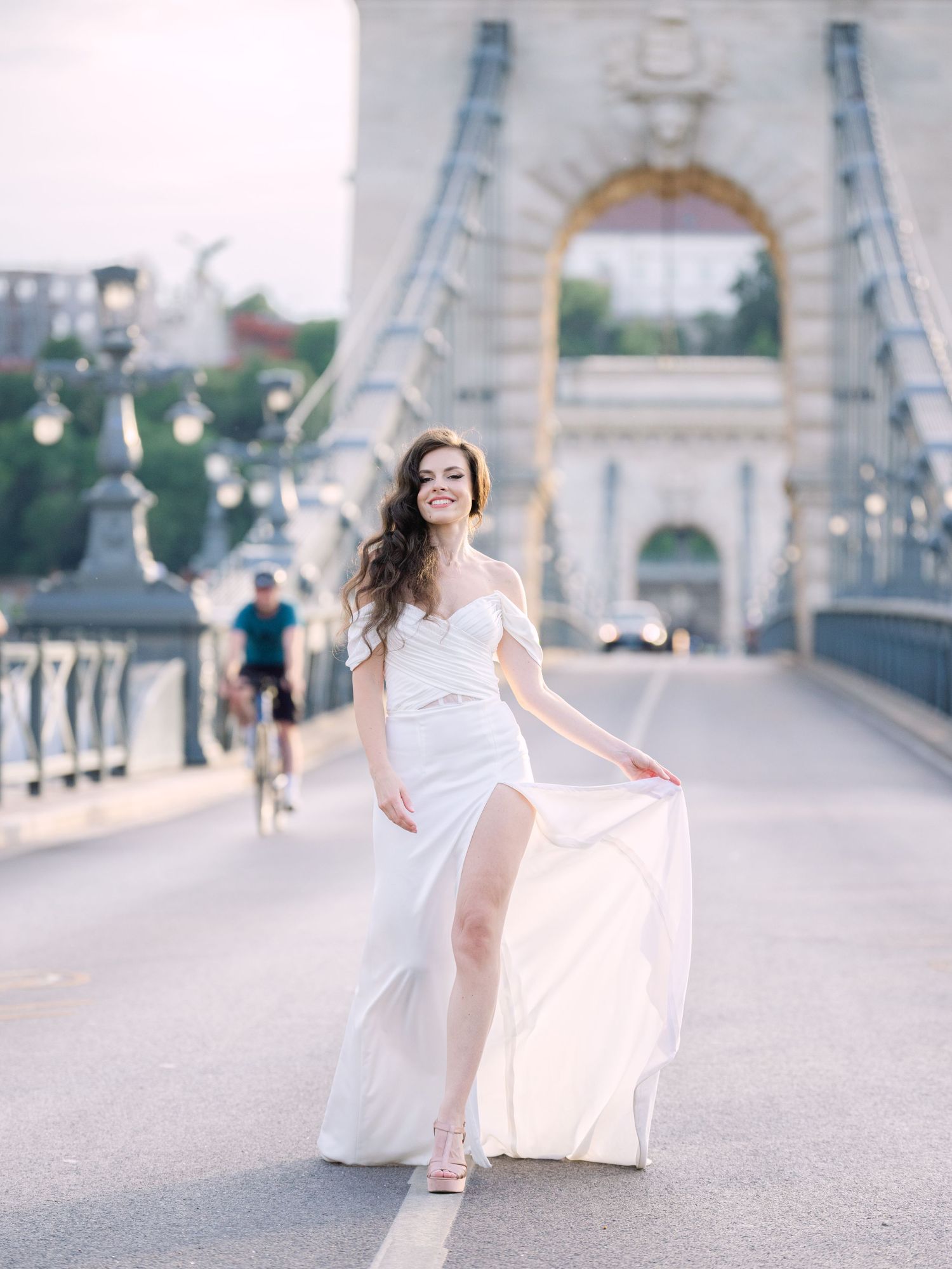 Elegant bride in a Leya Couture wedding dress posing on Budapest’s iconic Chain Bridge during a golden hour destination wedding editorial