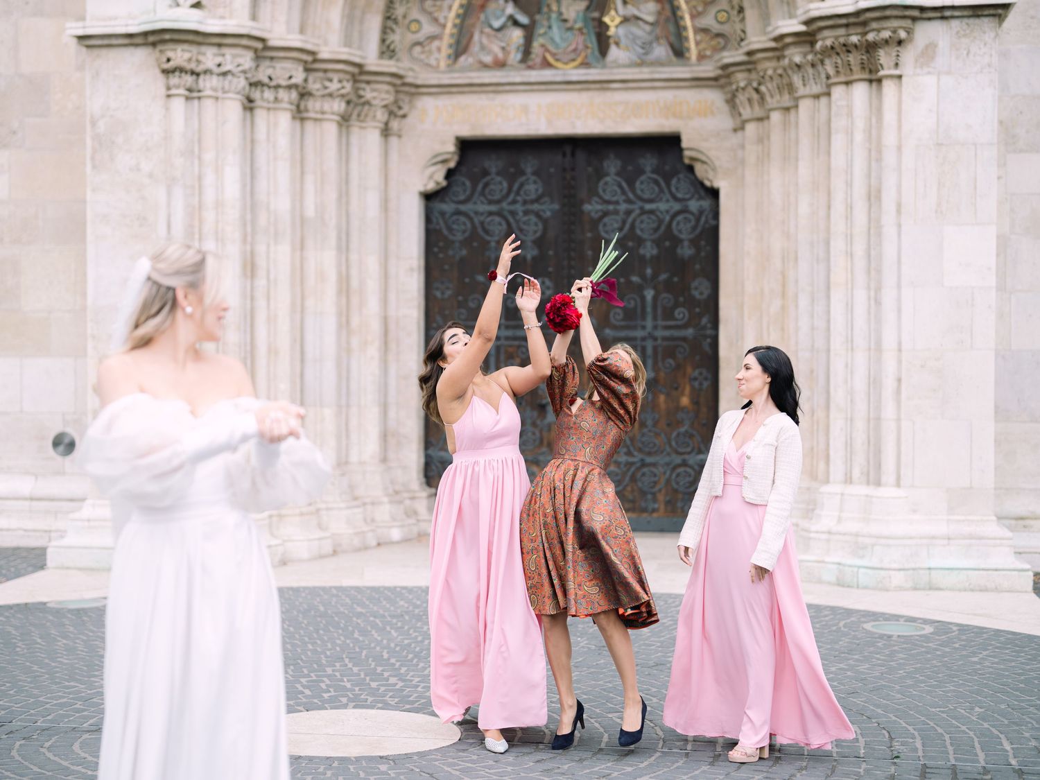 Bridal bouquet catching in front of St. Matthias Church at Buda Castle in Budapest after the ceremony, celebrating a joyful wedding moment