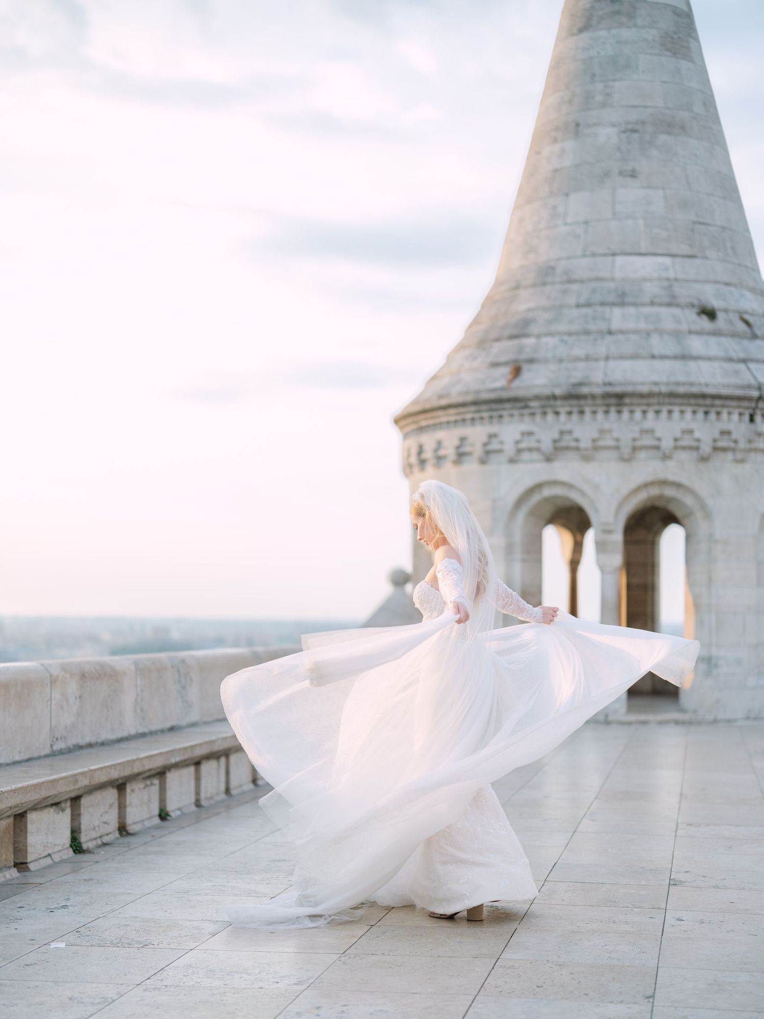 Elegant bride posing gracefully in a La Mariée dress at sunrise on Fisherman’s Bastion in Budapest, captured by Hang Pham Photography