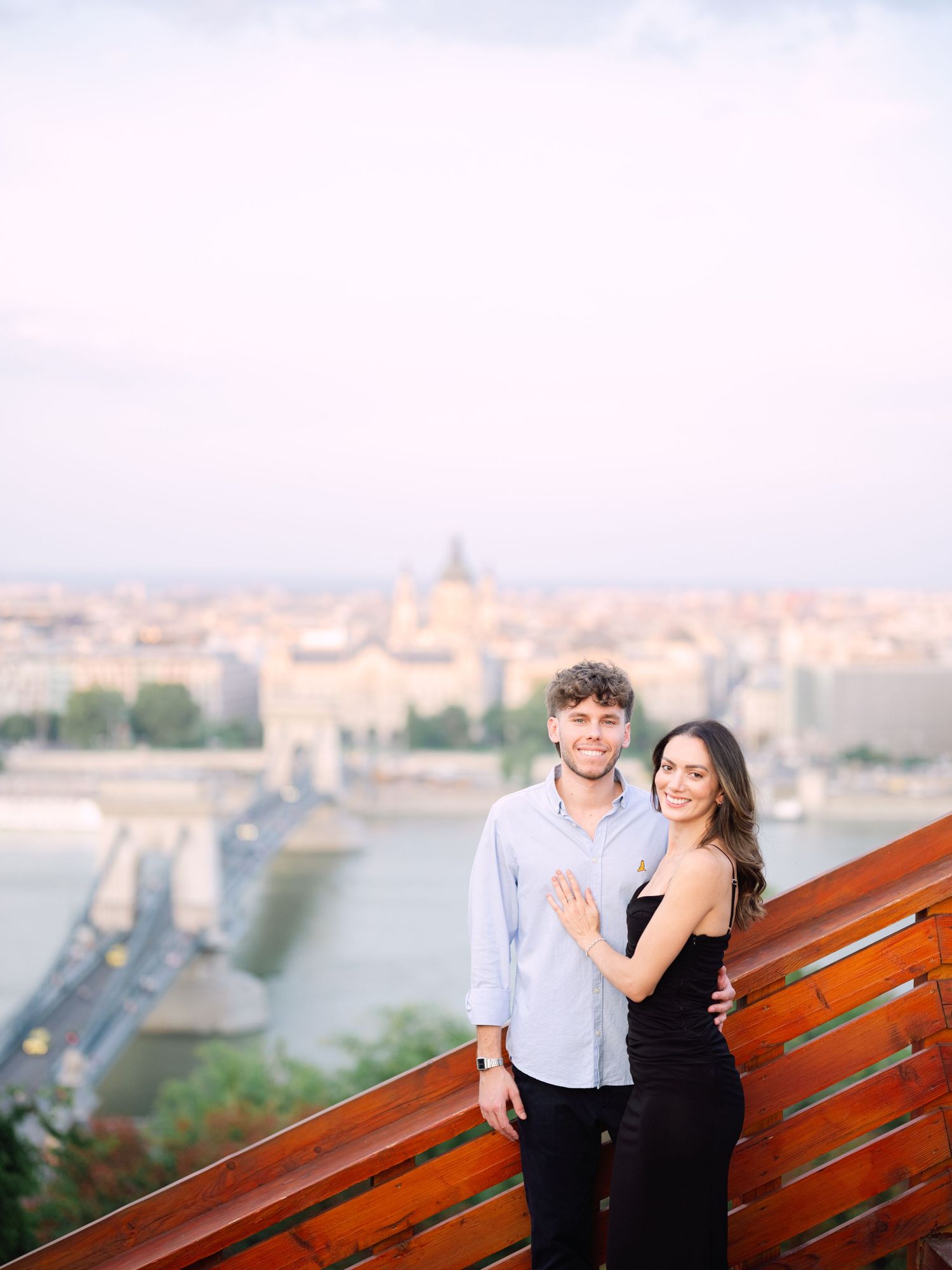 Elegant couple laughing and posing around Buda Castle in Budapest with scenic city views in the background during an couple portrait session