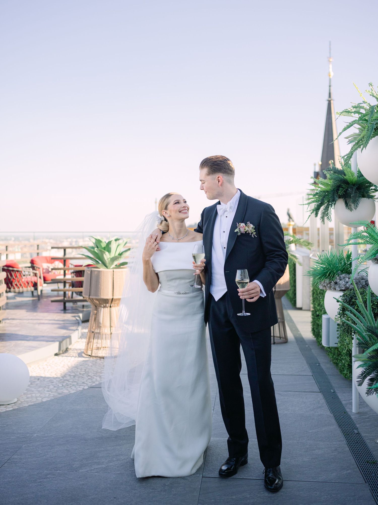 High-end couple posing for a creative wedding photoshoot at White Raven Skybar atop Hilton Budapest, featuring stunning city skyline views