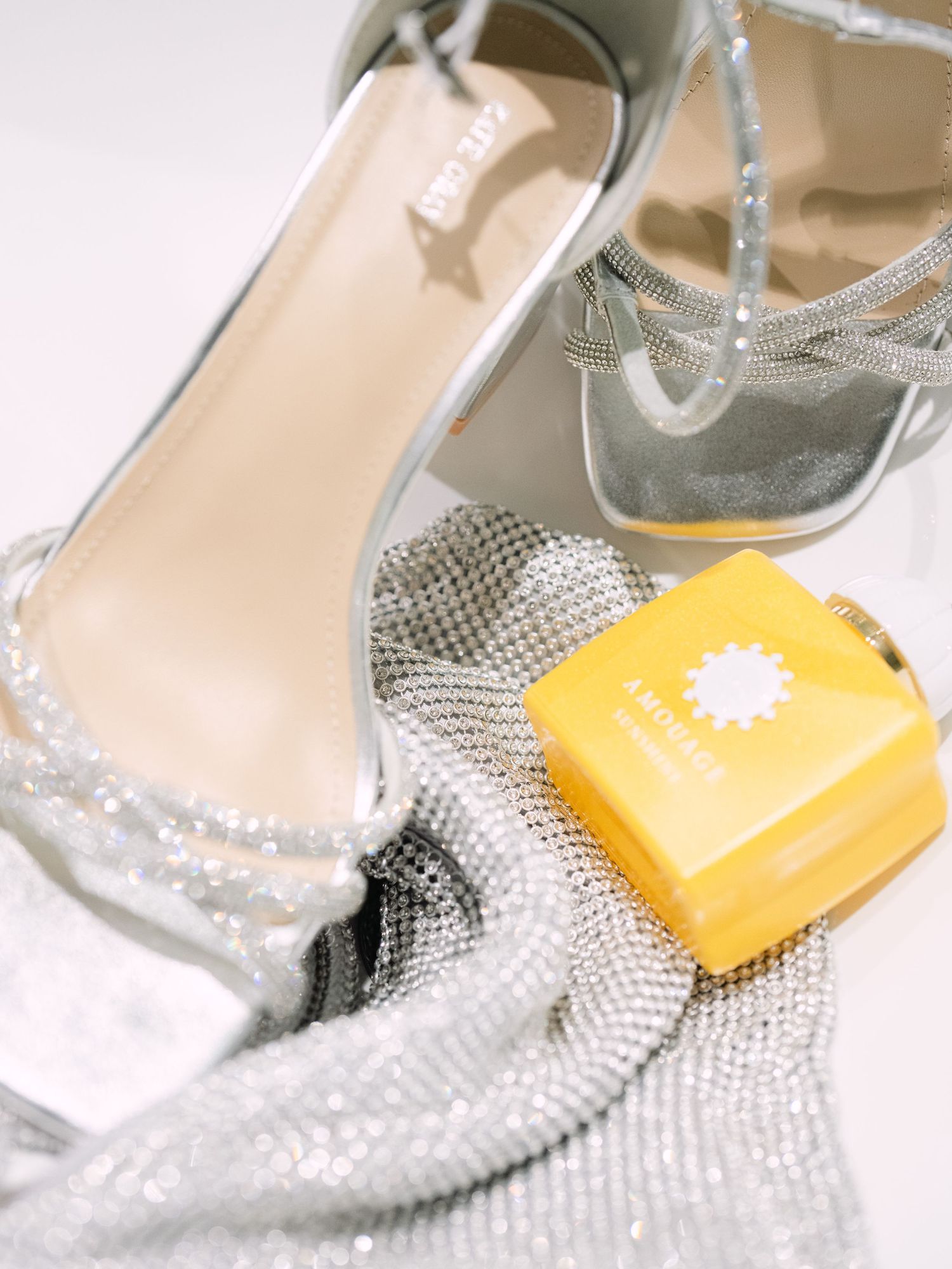 Wedding flatlay featuring elegant bridal shoes and a bottle of Amouage perfume, styled for a luxurious wedding detail shot