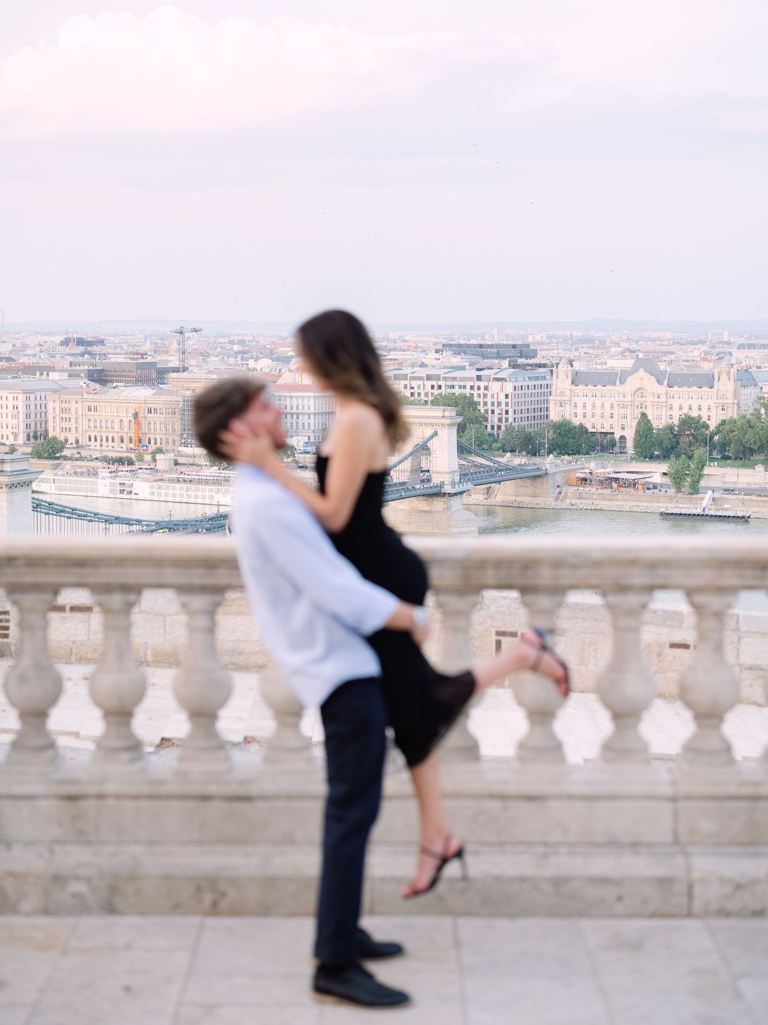 Elegant couple laughing and posing around Buda Castle in Budapest with scenic city views in the background during an couple portrait session