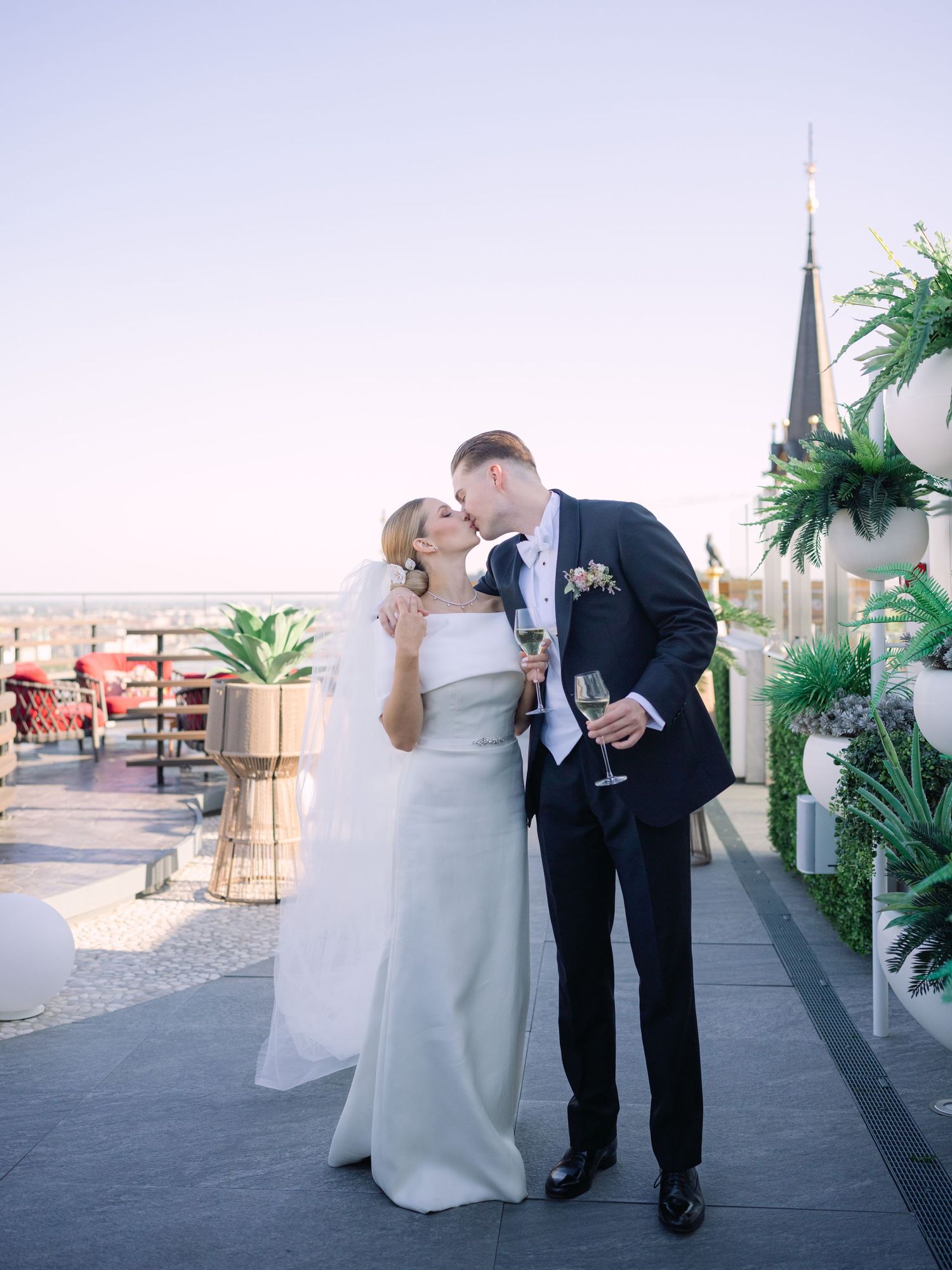 High-end couple posing for a creative wedding photoshoot at White Raven Skybar atop Hilton Budapest, featuring stunning city skyline views