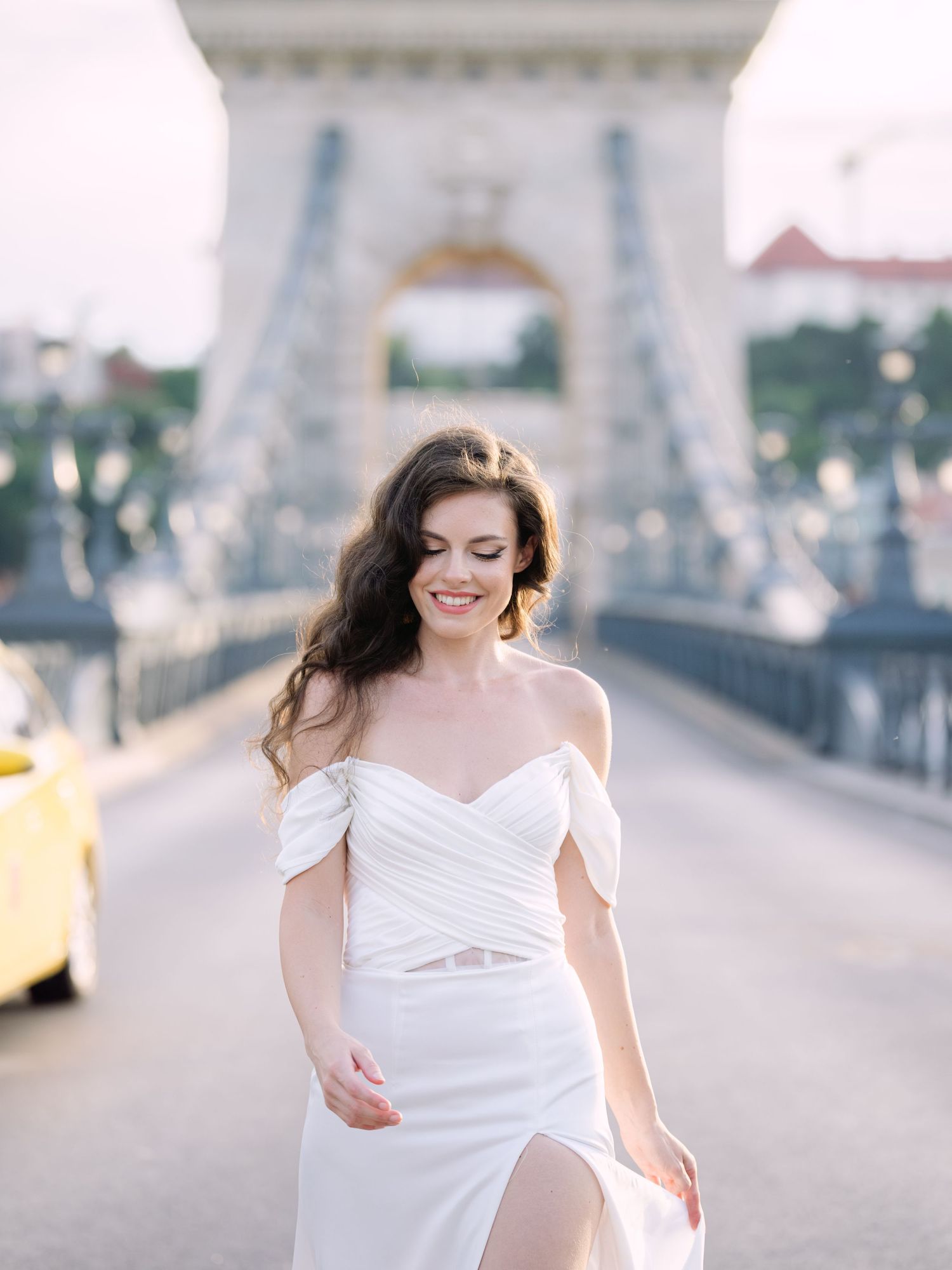 Elegant bride in a Leya Couture wedding dress posing on Budapest’s iconic Chain Bridge during a golden hour destination wedding editorial