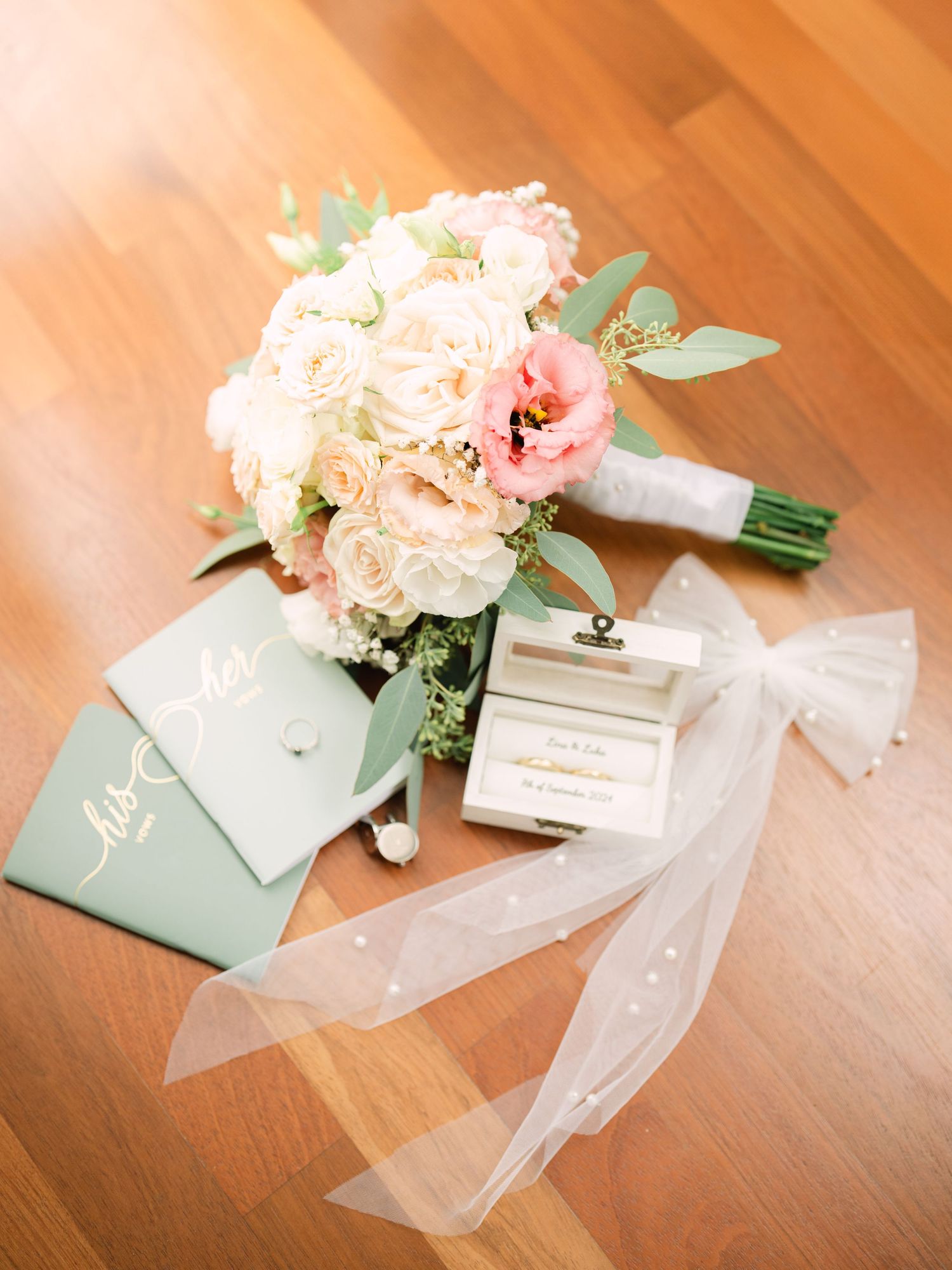 Wedding flatlay featuring elegant vows suite, gold wedding rings, and bridal bouquet, styled for a sophisticated luxury wedding detail shot
