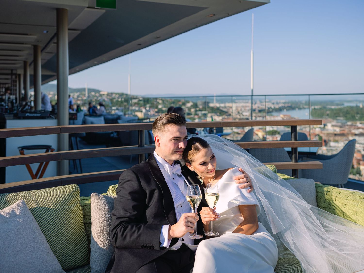 High-end couple posing for a creative wedding photoshoot at White Raven Skybar atop Hilton Budapest, featuring stunning city skyline views