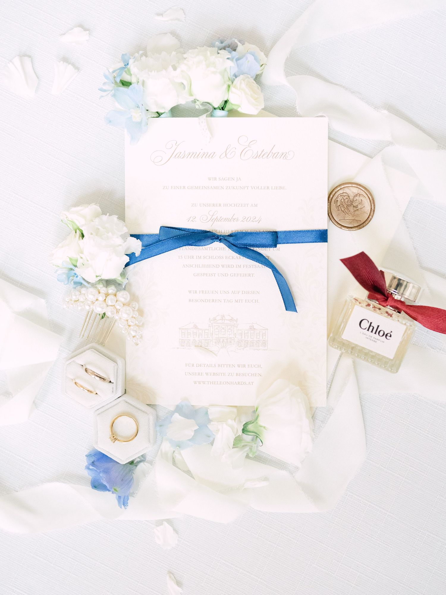 Wedding flatlay featuring elegant invitation suite, gold wedding rings, and Chloé parfum bottle, styled for a luxury wedding detail shot