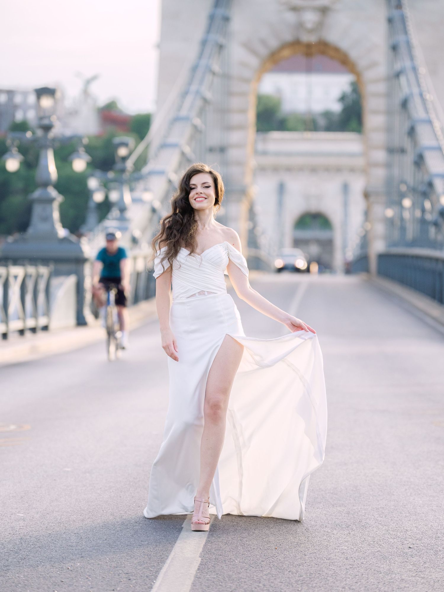 Elegant bride in a Leya Couture wedding dress posing on Budapest’s iconic Chain Bridge during a golden hour destination wedding editorial