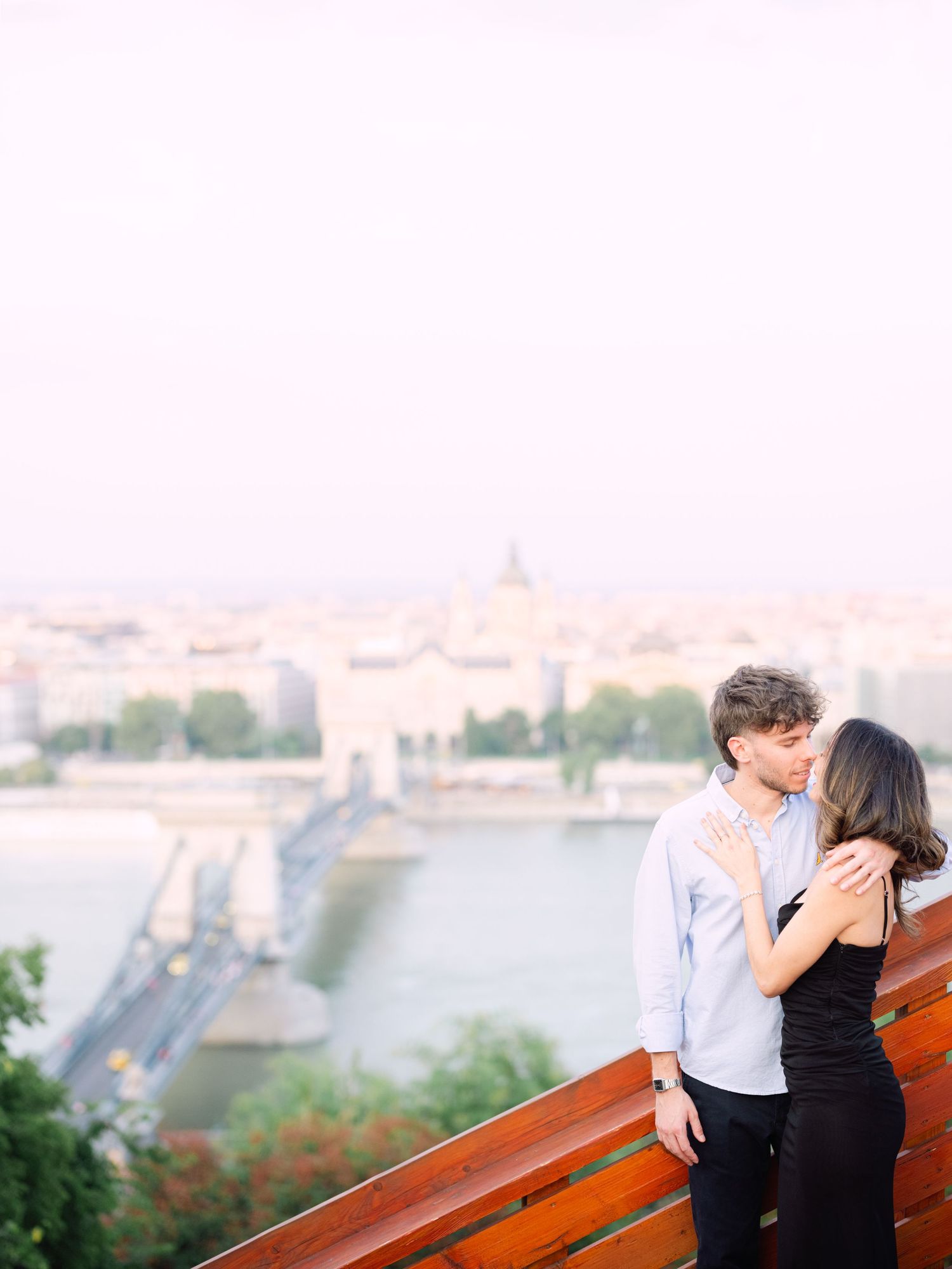 Elegant couple laughing and posing around Buda Castle in Budapest with scenic city views in the background during an couple portrait session