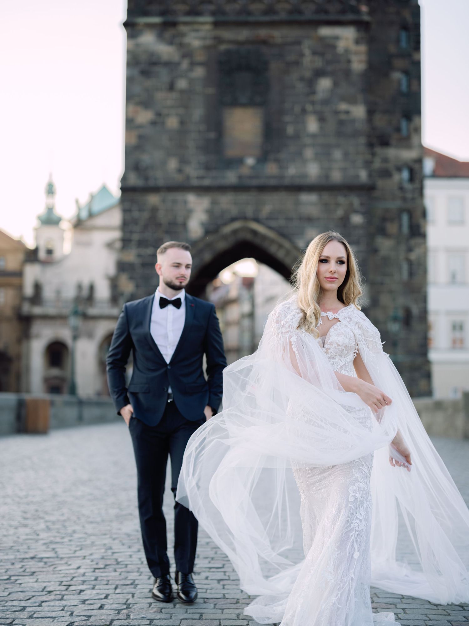 Elegant couple posing romantically on Charles Bridge in Prague during a destination elopement, beautifully captured by Hang Pham Photography