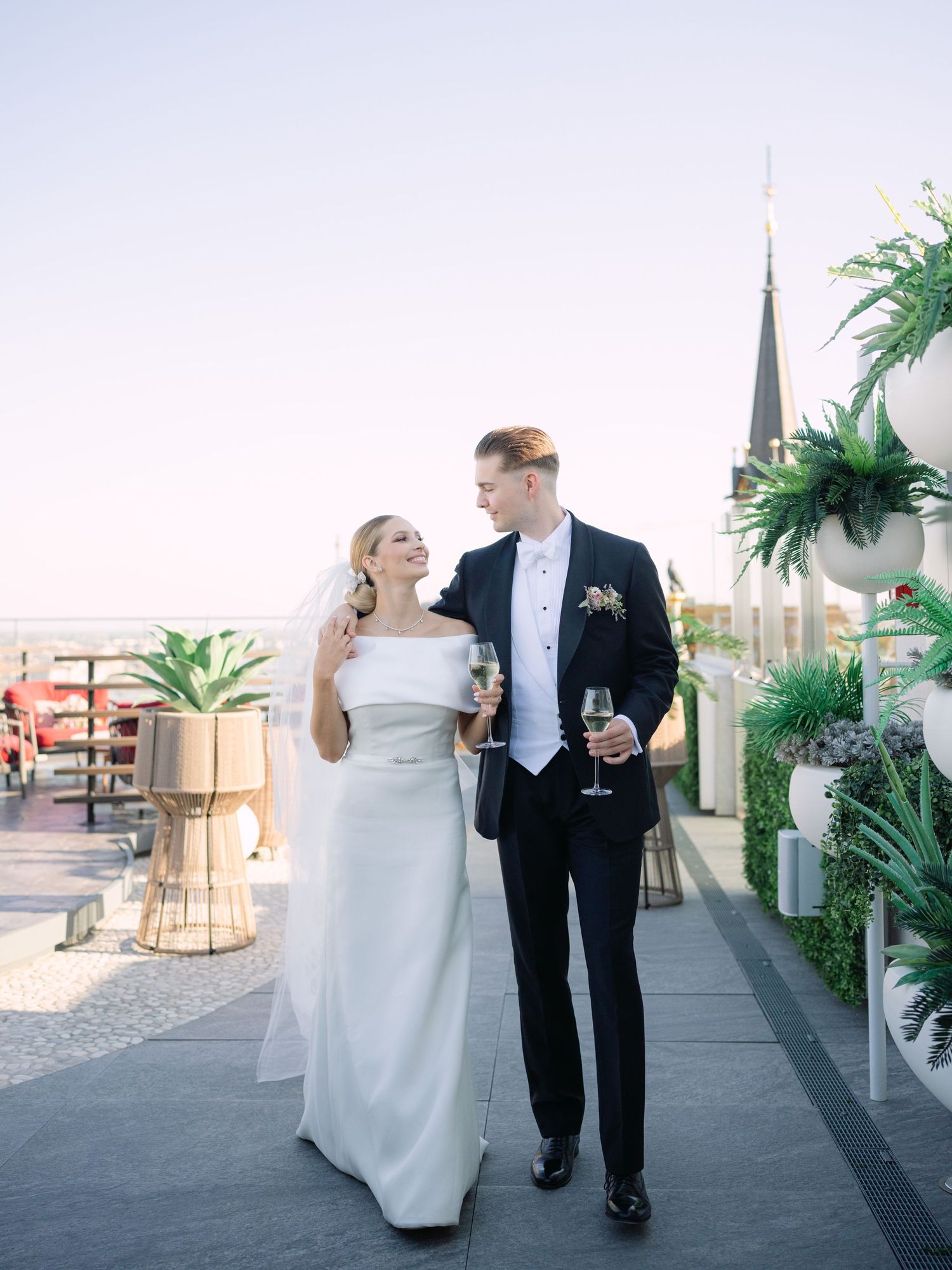 High-end couple posing for a creative wedding photoshoot at White Raven Skybar atop Hilton Budapest, featuring stunning city skyline views