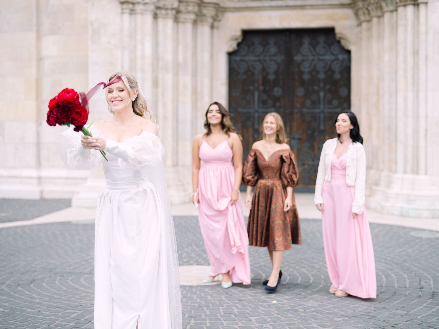 Bride tossing her bouquet in front of St. Matthias Church at Buda Castle in Budapest after the ceremony during a destination wedding