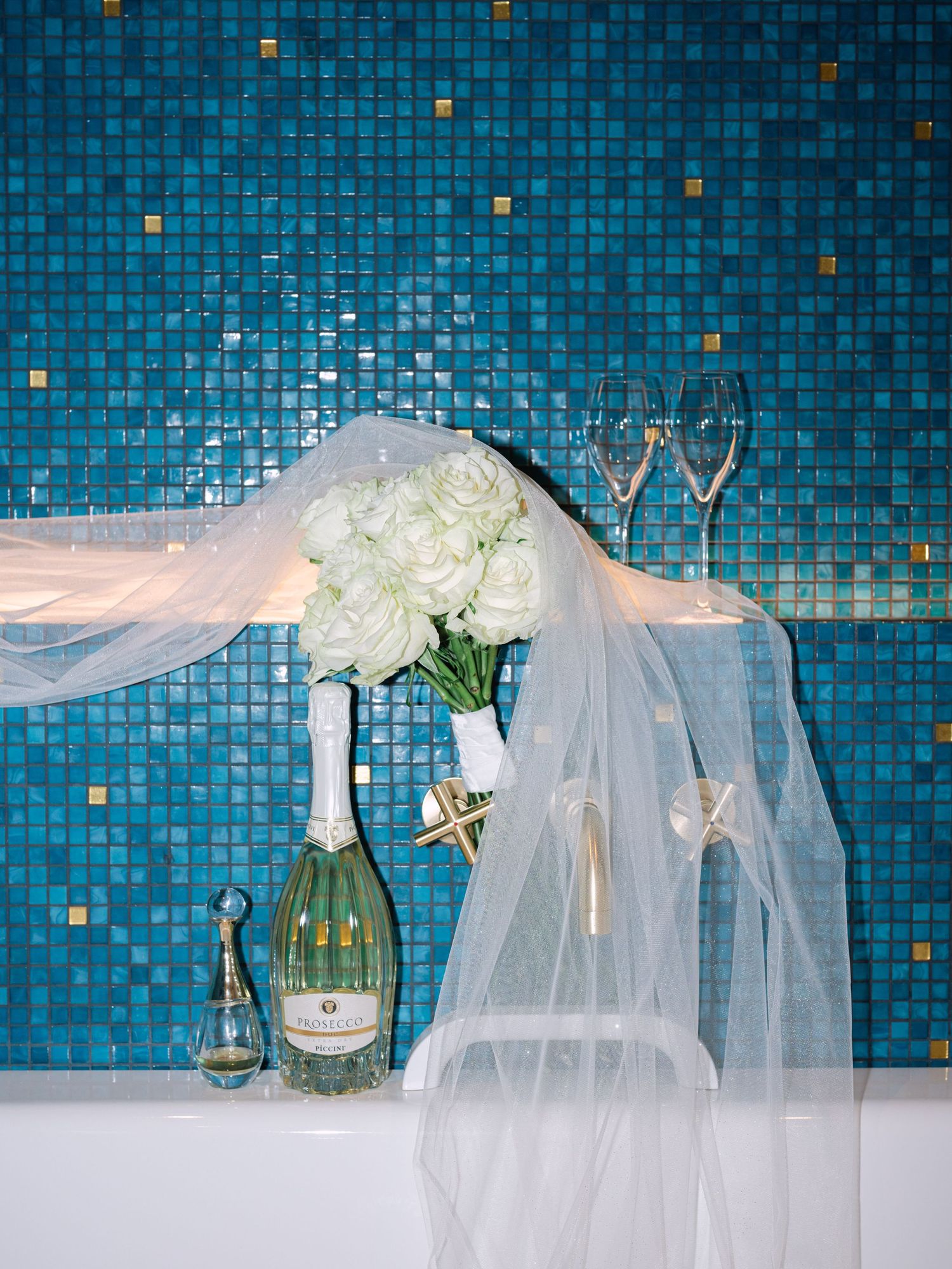 Wedding flash shot featuring champagne, bridal bouquet, parfum, and veil styled elegantly in the luxurious bathroom of Matild Palace