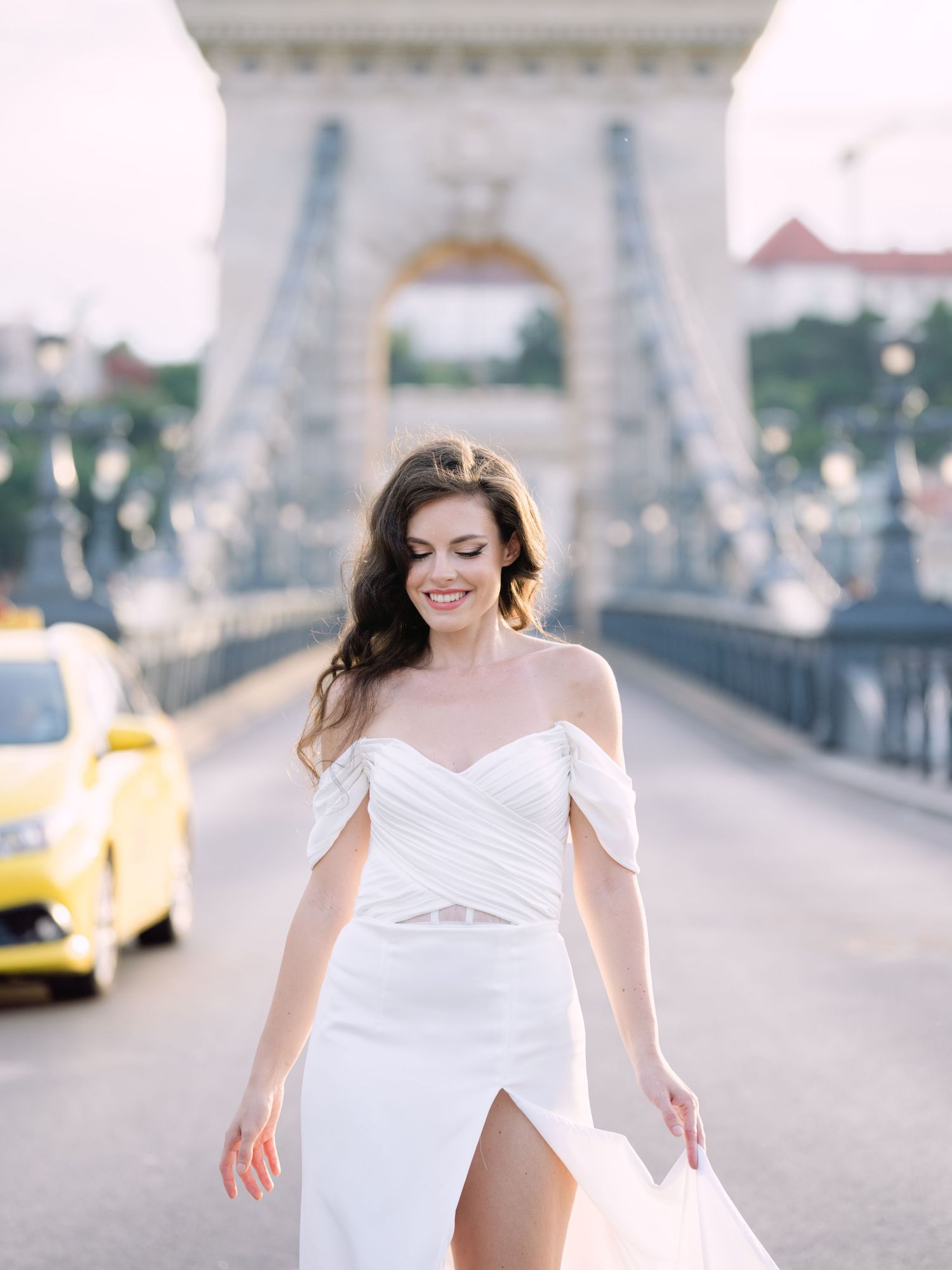 Elegant bride in a Leya Couture wedding dress posing on Budapest’s iconic Chain Bridge during a golden hour destination wedding editorial