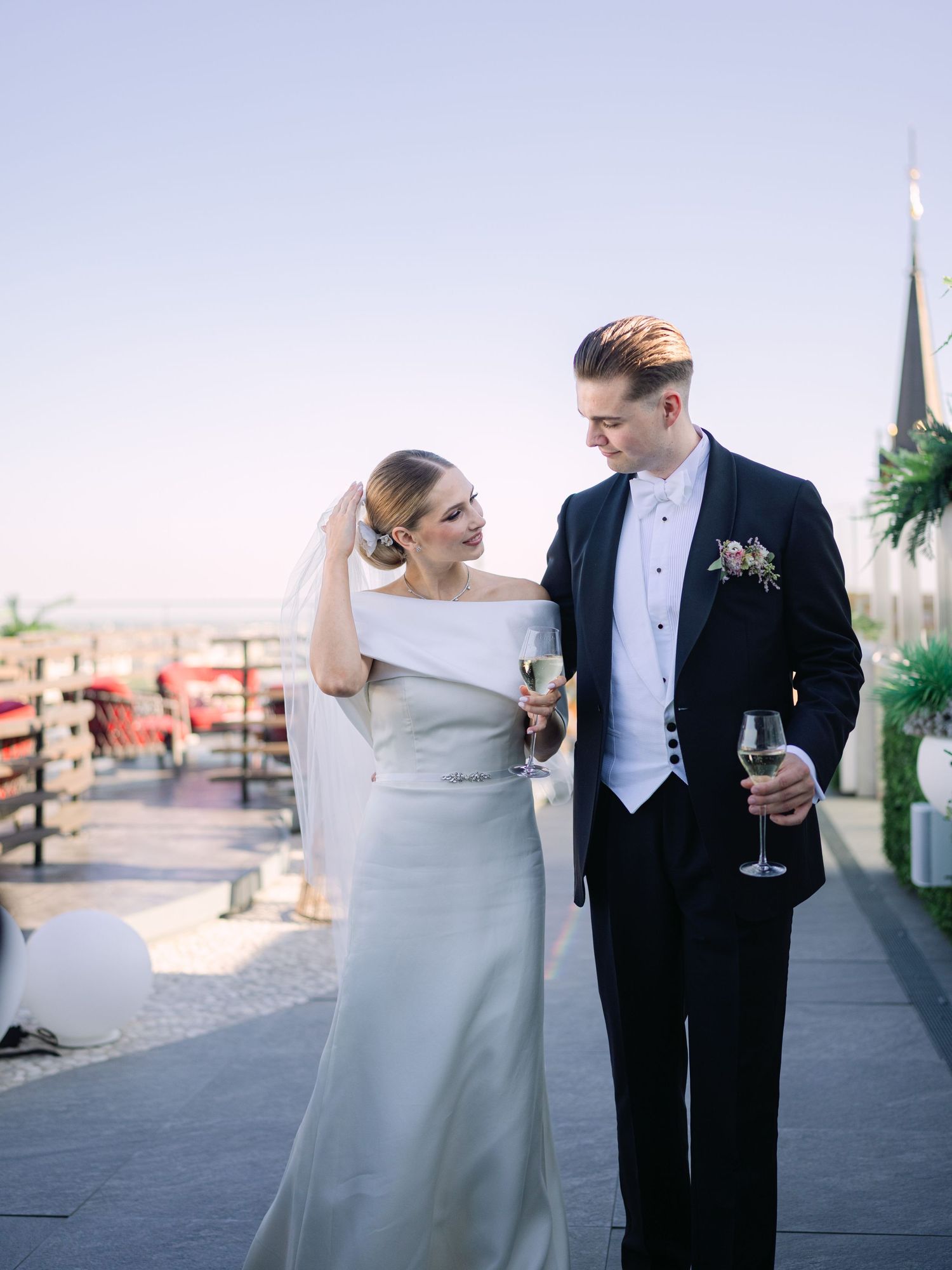 High-end couple posing for a creative wedding photoshoot at White Raven Skybar atop Hilton Budapest, featuring stunning city skyline views