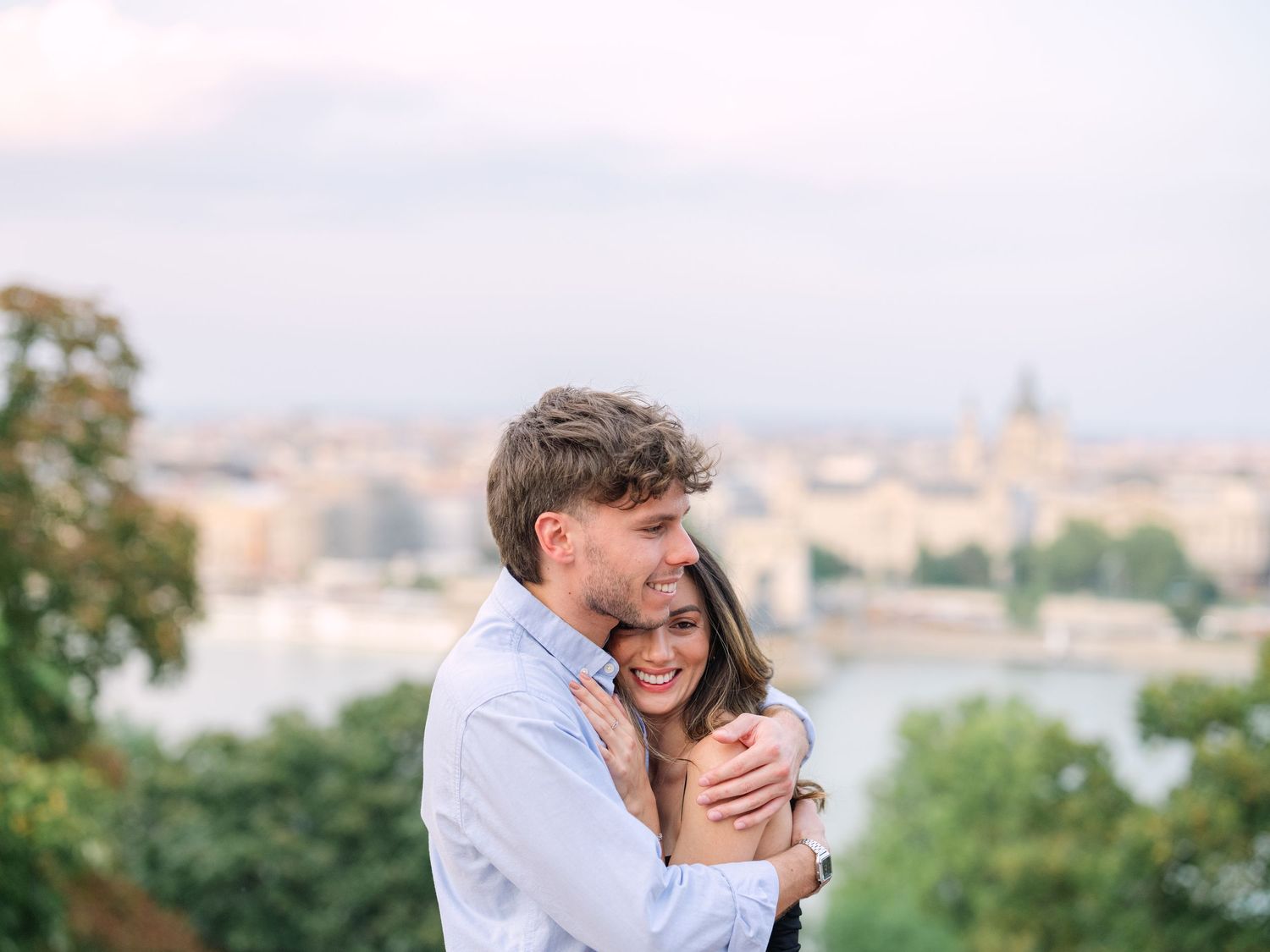 Elegant couple laughing and posing around Buda Castle in Budapest with scenic city views in the background during an couple portrait session