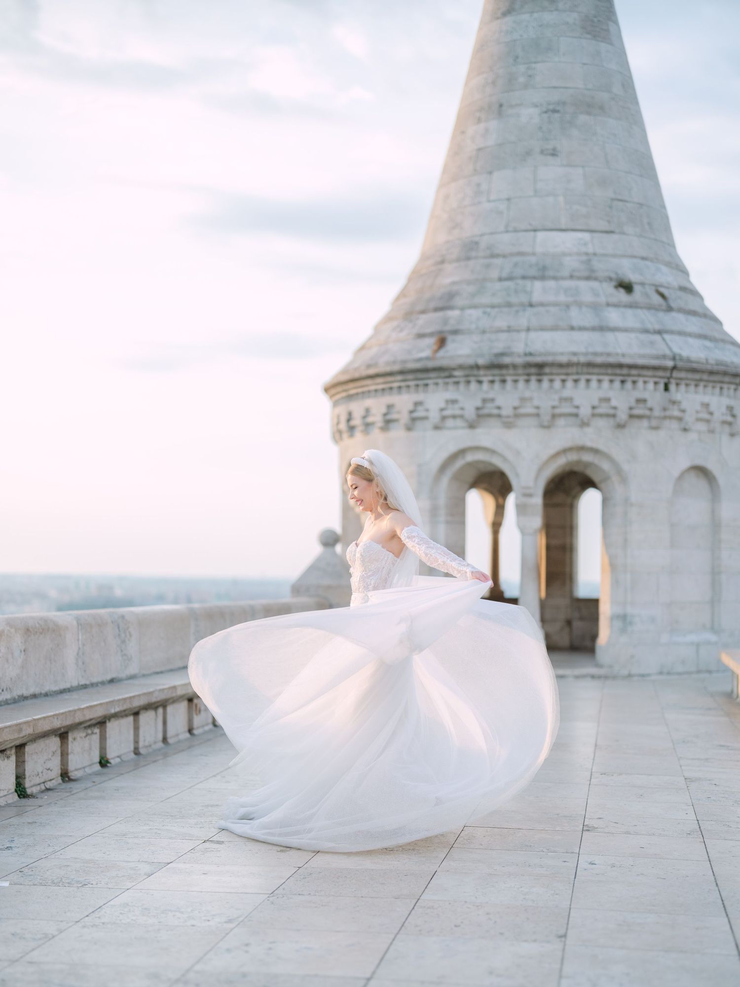 Elegant bride posing gracefully in a La Mariée dress at sunrise on Fisherman’s Bastion in Budapest, captured by Hang Pham Photography