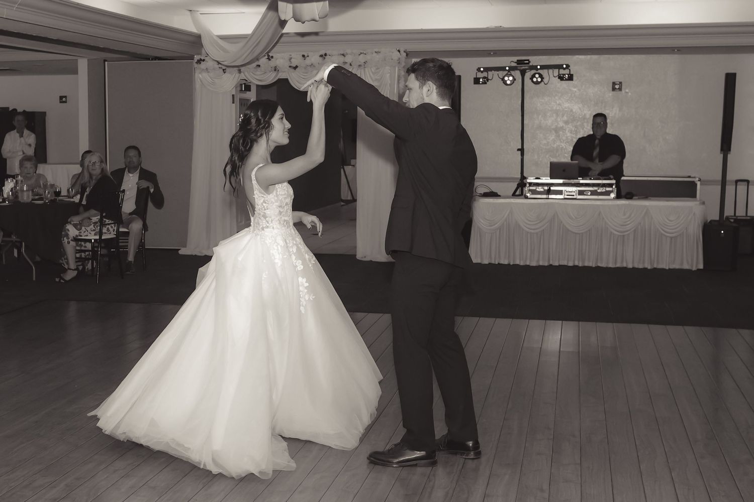 Black and white photo of bride and groom sharing their first dance at a wedding reception.