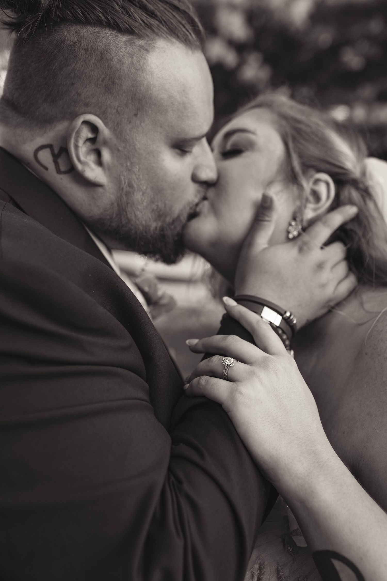 Black and white photo of a bride and groom sharing a romantic kiss on their wedding day.