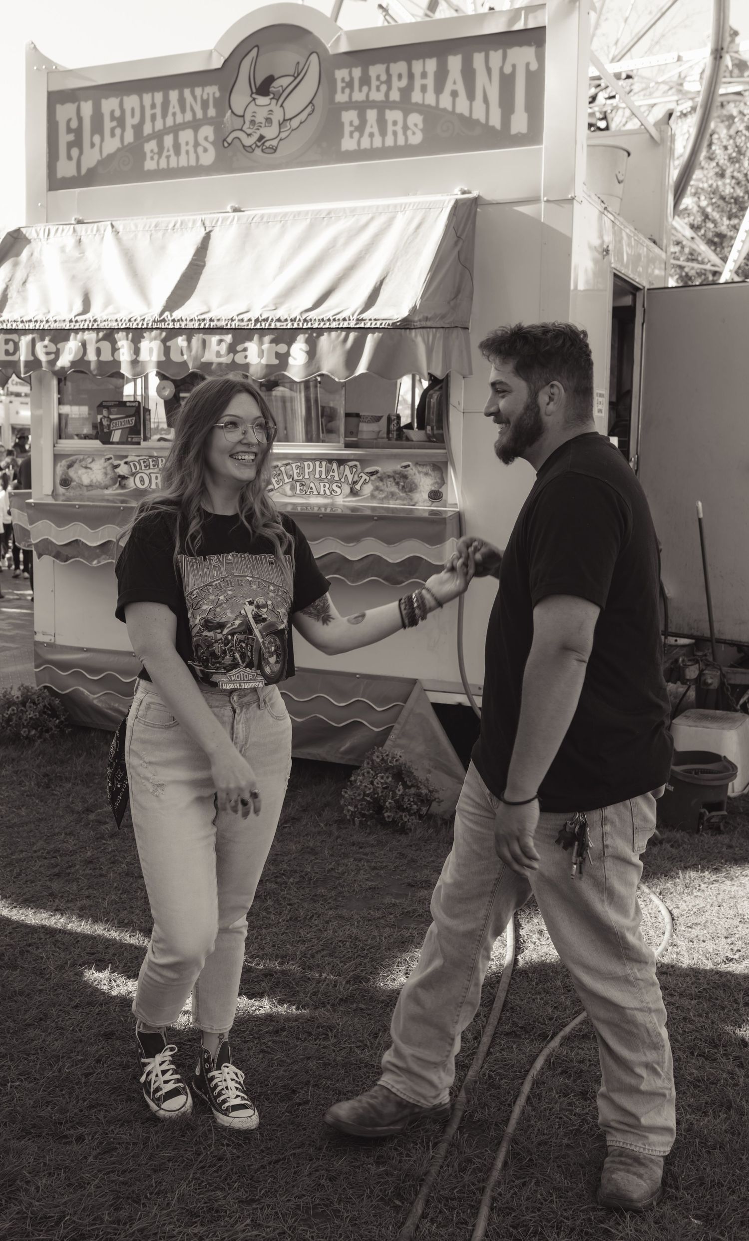 Couple laughing together in black and white photo at a carnival Elephant Ears stand.