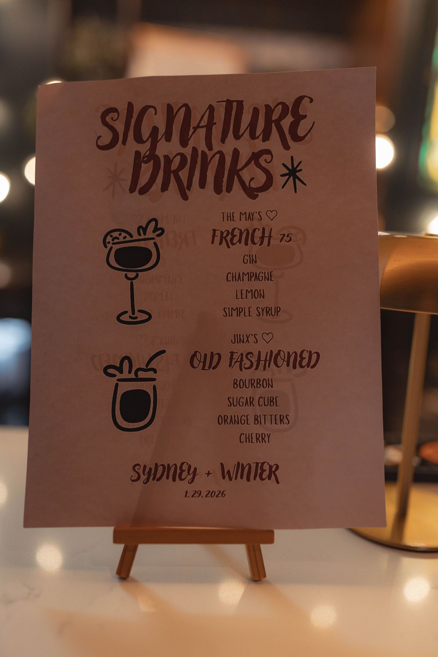Wedding signature drinks menu sign for Sydney and Winter on wooden easel.