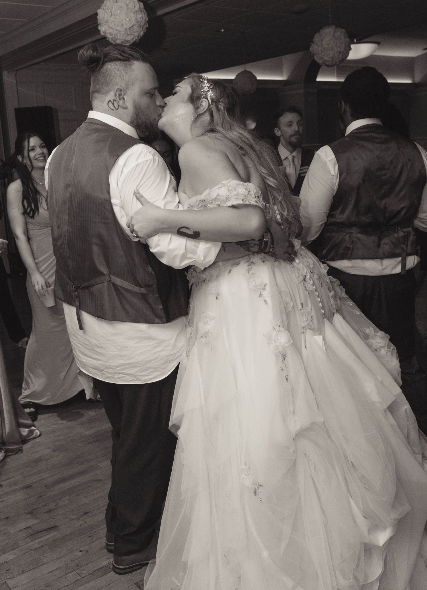 Bride and groom share a romantic kiss on the dance floor in black and white wedding photography.